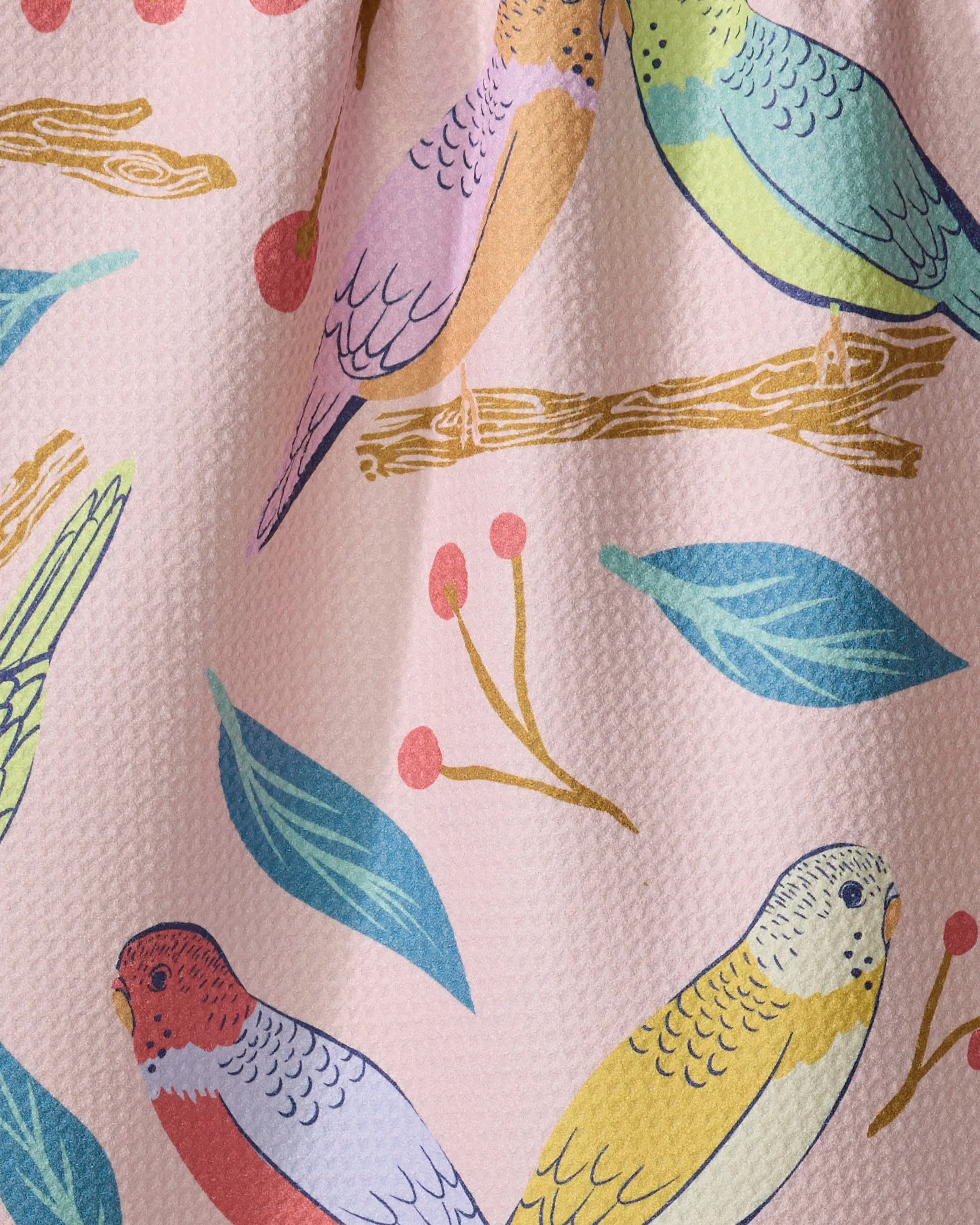 Elisabeth Wing’s "Berries and Budgies" tea towel features colorful illustrated parakeets on leafy, berry-laden branches set against a textured light pink background, crafted from recycled materials for a charming touch.