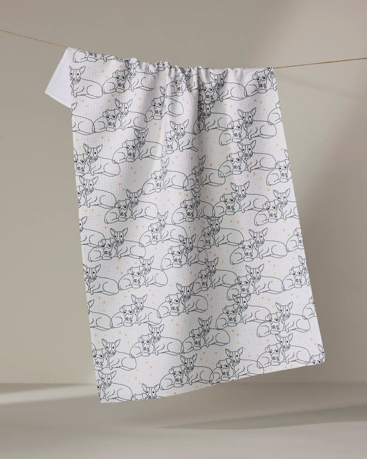 The Berry and Louie tea towel by Sweet Simple Vegan, featuring quick-drying white fabric with black line art of resting cats and small orange dots, is displayed hanging against a neutral backdrop.