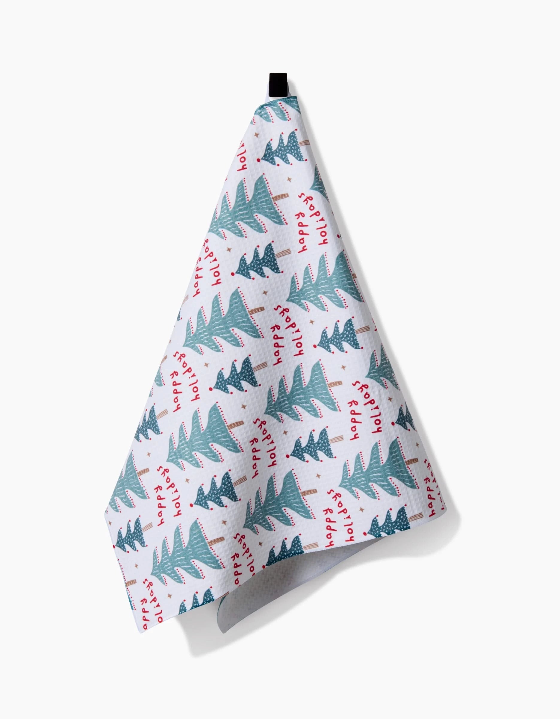 The Berry Happy Holidays kitchen towel by Roxy Marj hangs from a black loop, with green Christmas trees and red Happy Holidays text—an easy, festive way to add seasonal cheer to your kitchen decor.