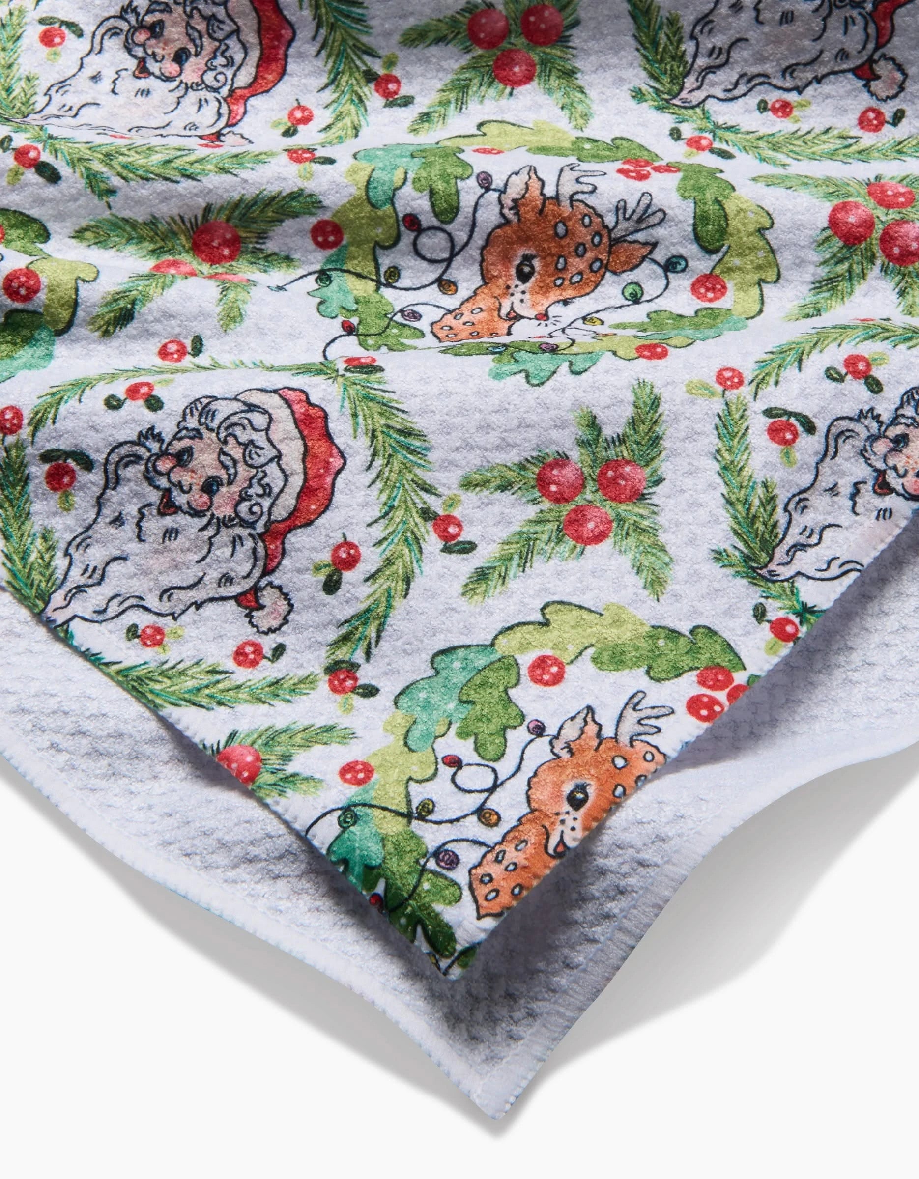 The Berry Retro Holiday kitchen towel by Sara Mari features festive Santa, reindeer, holly, and berries, crafted from recycled materials with a white textured corner border.