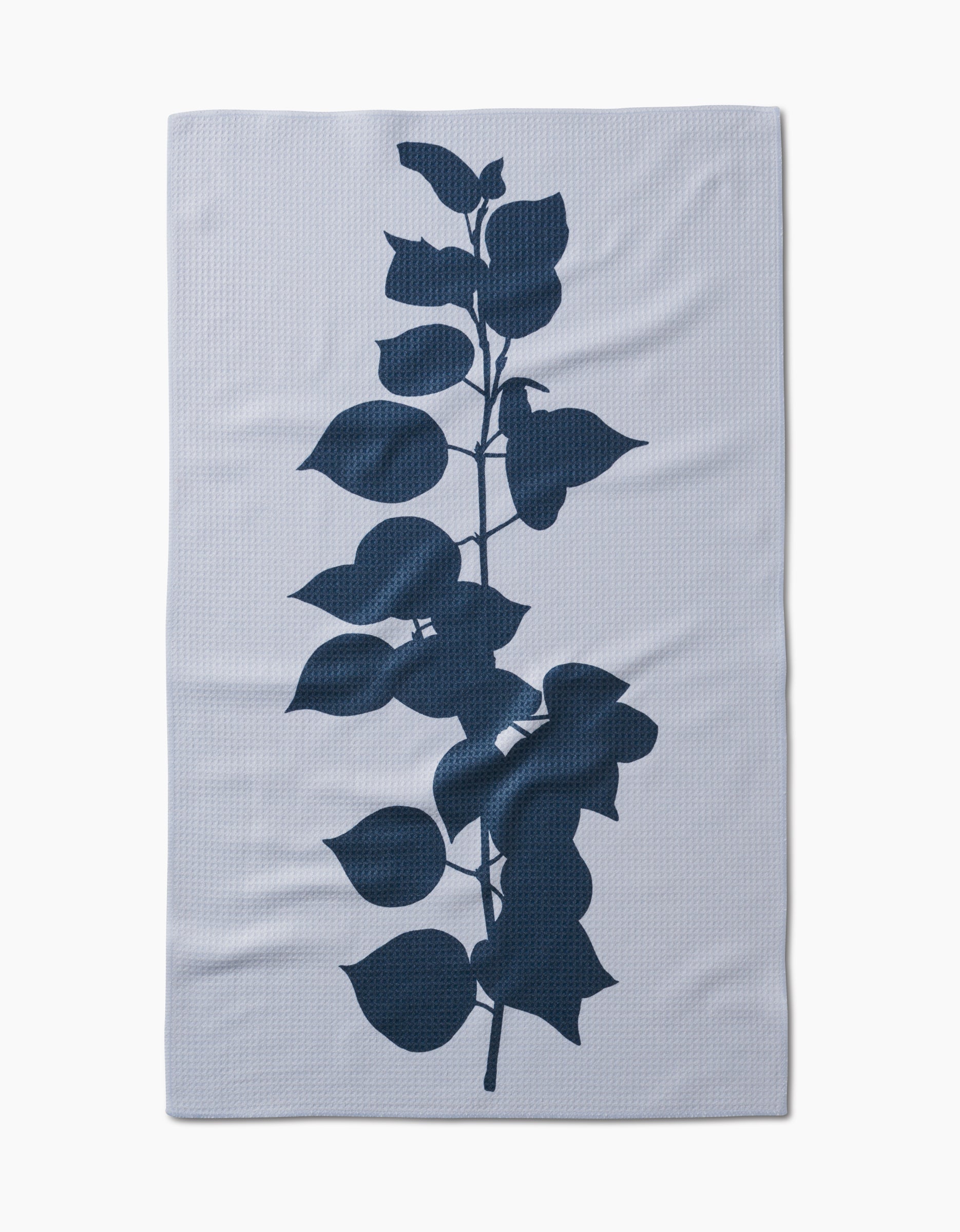 The Birch Tea Towel by PrintedPlant is a white rectangular towel made from recycled materials, featuring a bold dark blue botanical branch silhouette in the center.