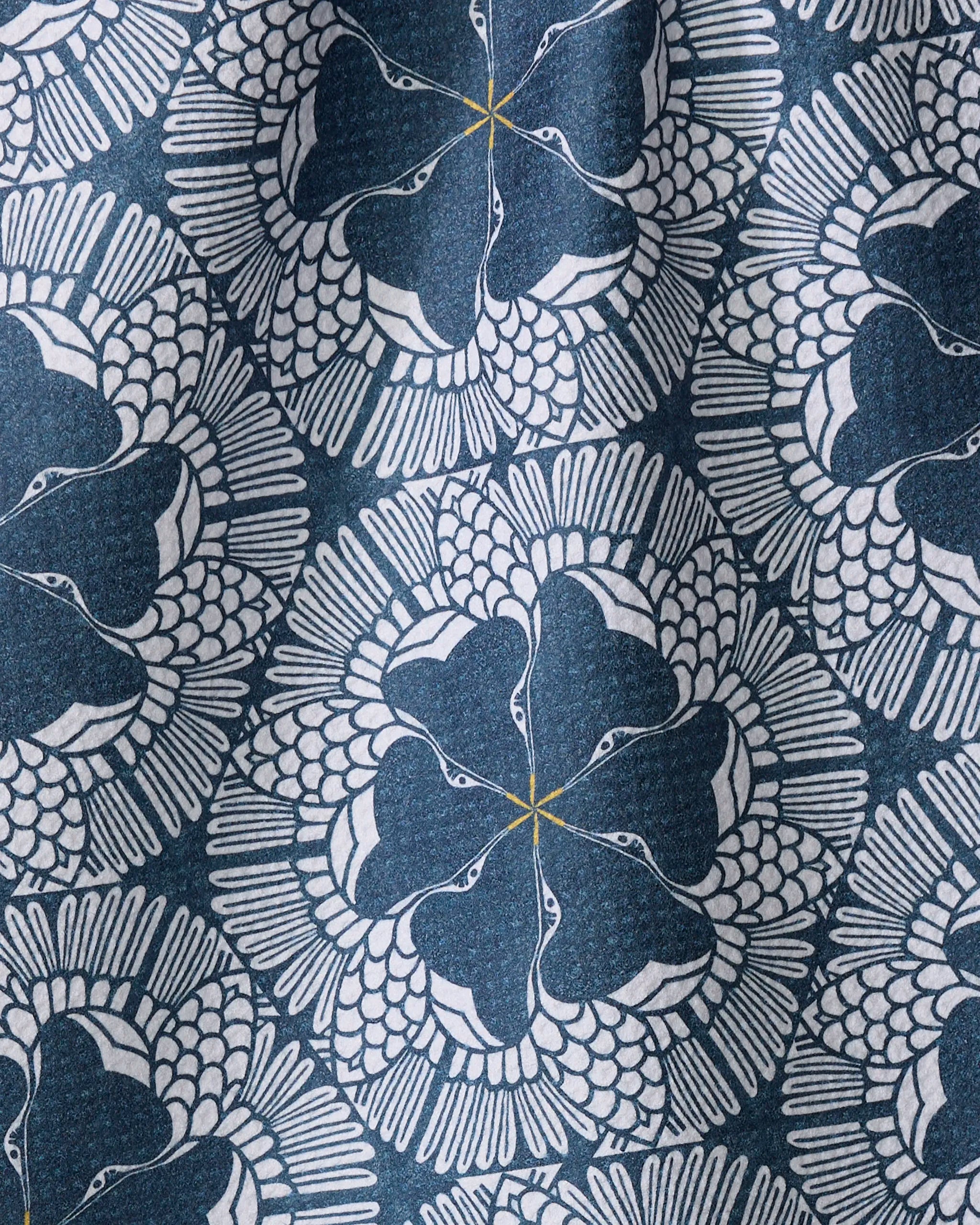 The "Birds of a Feather" tea towel by Renee Fly features a symmetrical, geometric pattern of stylized white cranes forming circles on dark blue with yellow centers. Made from recycled materials.