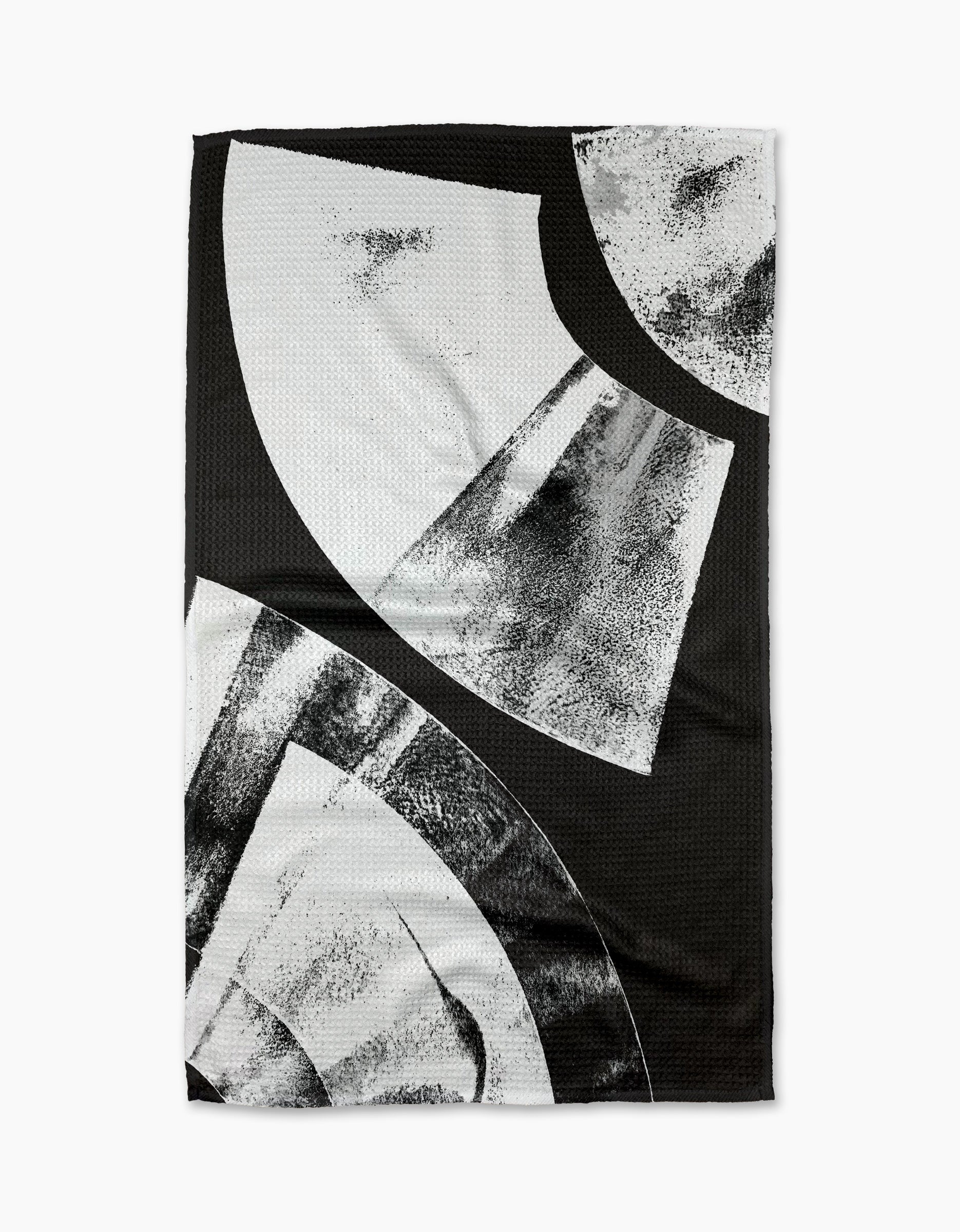 The Skye Walker Black Graphite Shift is a black ultra-absorbent tea towel with bold abstract white and gray geometric shapes and textured brushed patterns, offering a modern, artistic look.