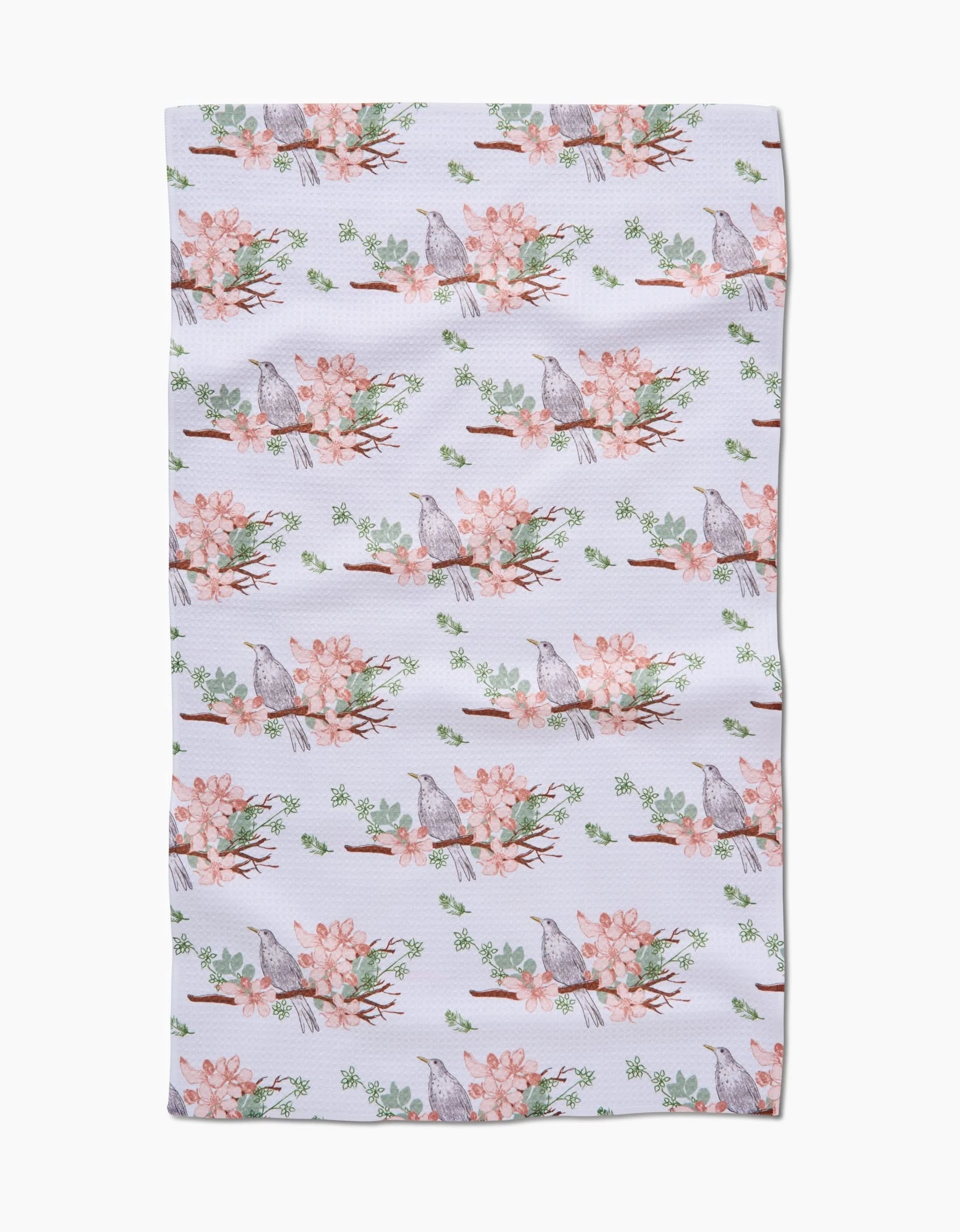 The Linda Fox Blackbird and Blossom towel features ultra-absorbent Geoweave fabric with a white background and a repeating pattern of gray birds on branches with pink flowers and green leaves.