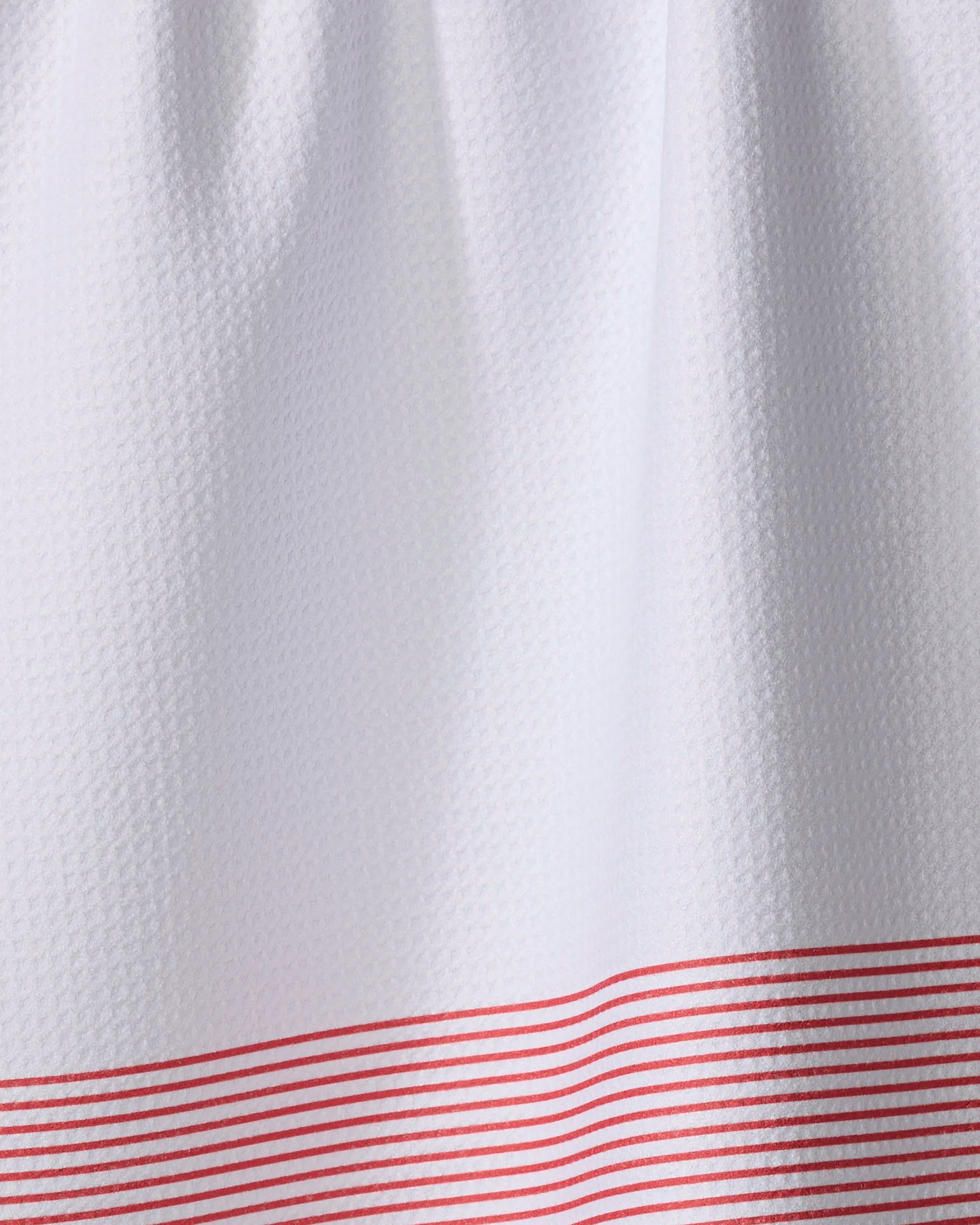 The Buy Guide’s Blank Space - Candy Apple is a white textured tea towel made from recycled materials, featuring a subtle waffle pattern and several horizontal red lines near the bottom edge.