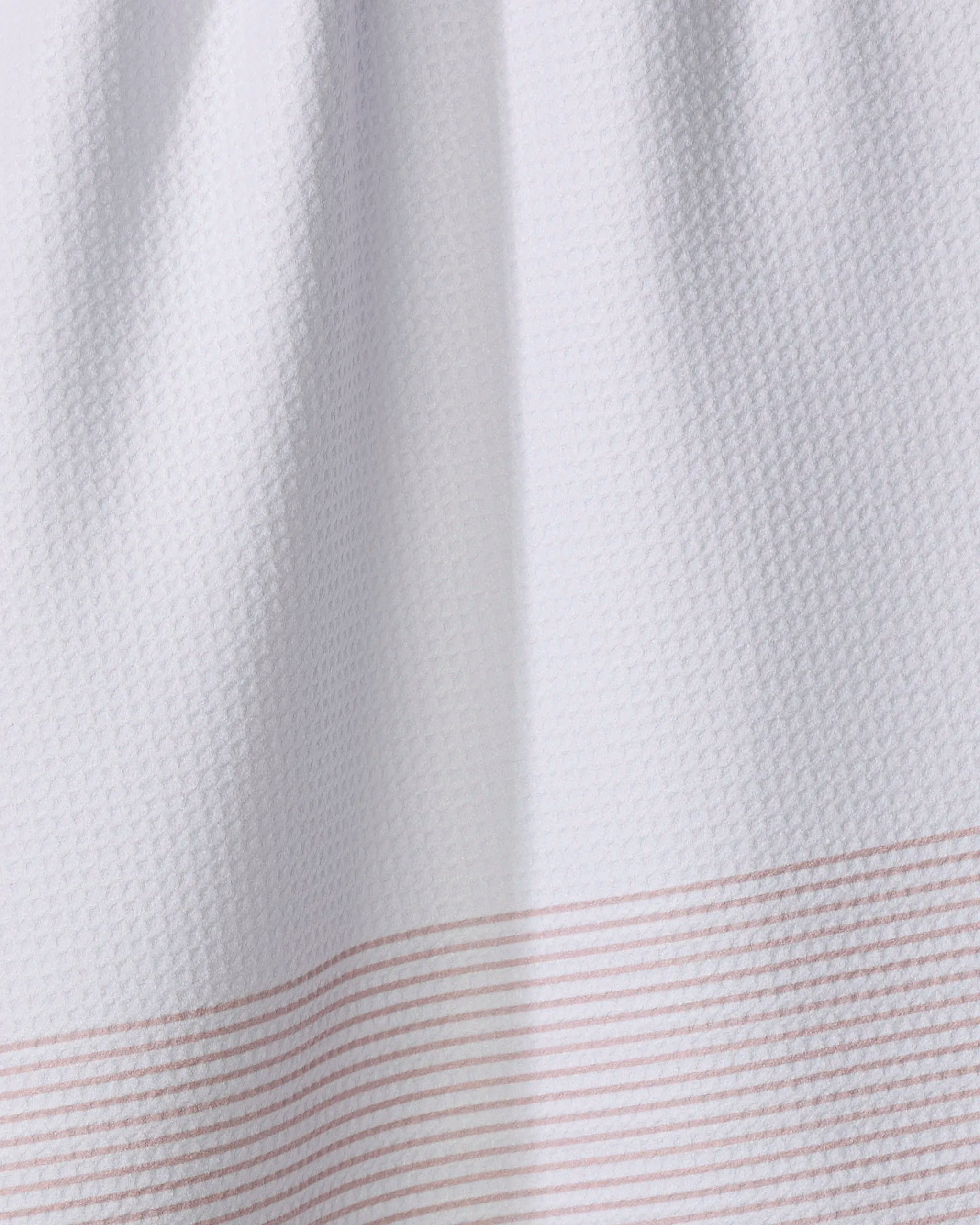 The Buy Guide's Blank Space - Dusty Rose tea towel features a white textured waffle pattern with thin pink stripes near the edge. Made from recycled materials, it's soft, absorbent, practical, and eco-friendly.