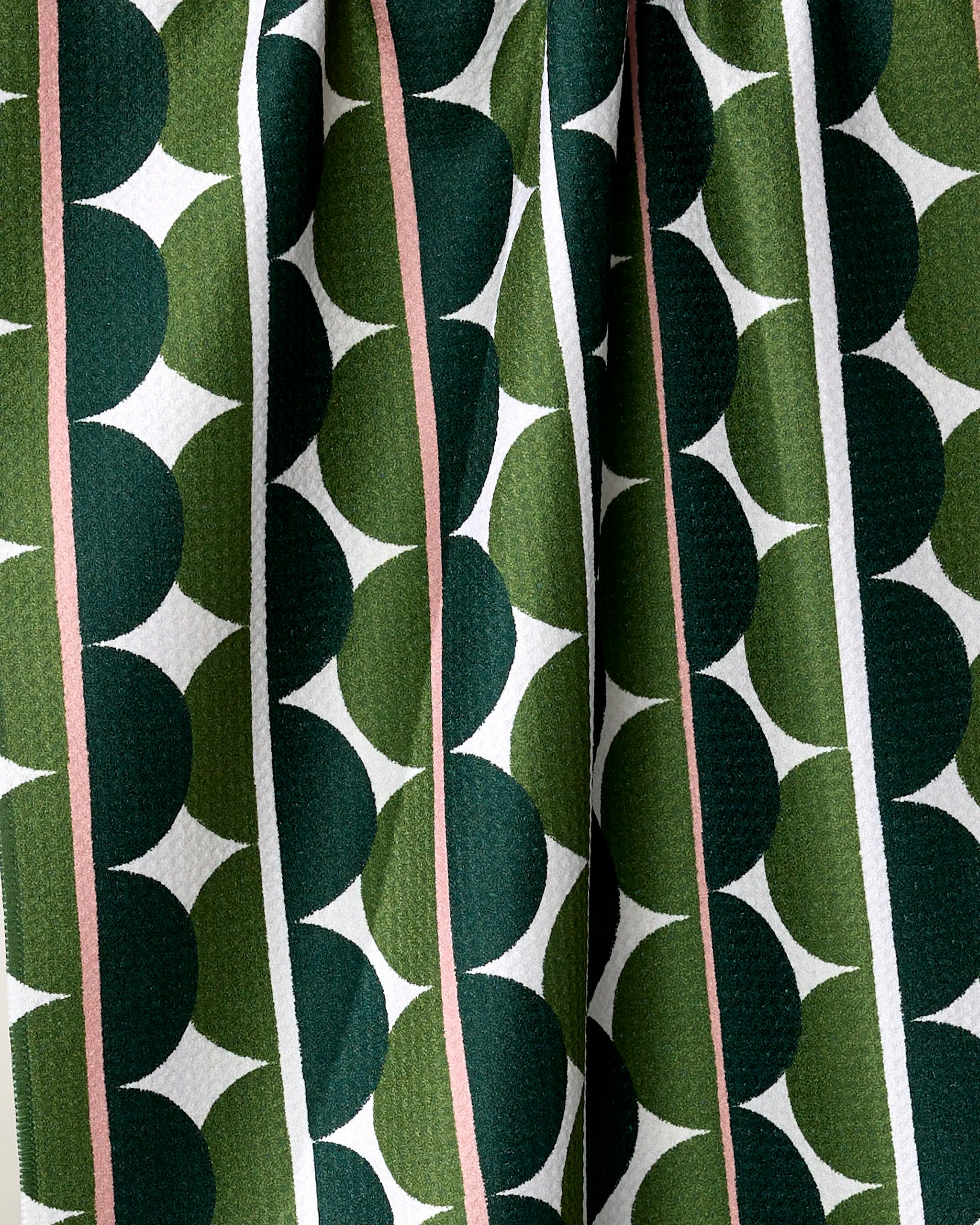 Close-up of Blockprint Eclipse by Rachel Parker, an eco-friendly fabric featuring dark and light green overlapping circles, pink and white vertical stripes, and a textured surface with soft folds—ideal for a stylish tea towel.