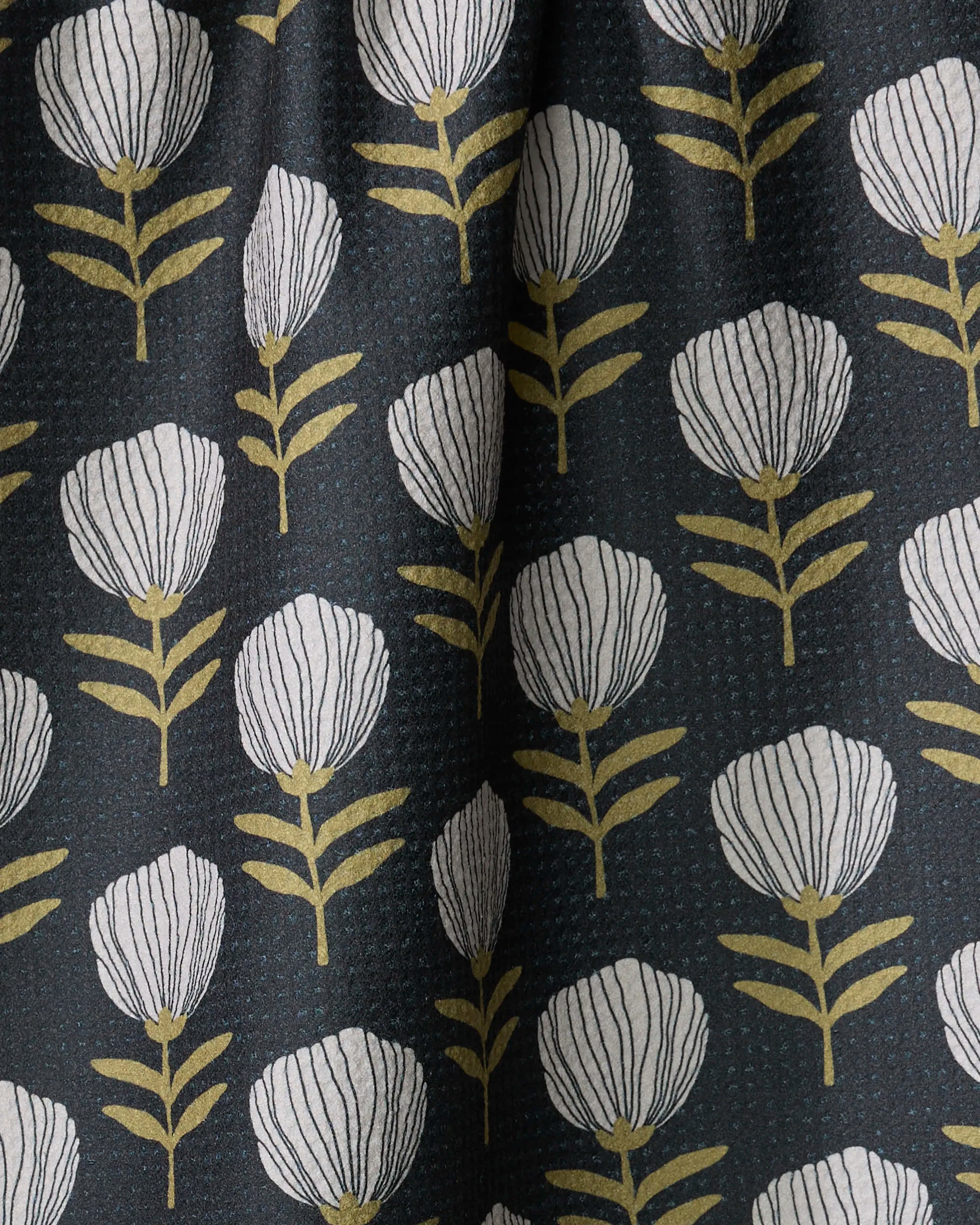 The Blomma tea towel by Anna Christian features a black fabric with white, stylized flowers and gold stems in vertical rows. Ultra-absorbent, it adds elegance and functionality to your kitchen.