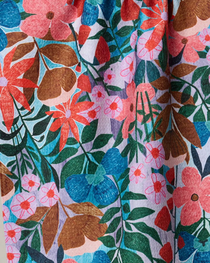 Bloom Entangled by Lisa Nelson is an ultra-absorbent tea towel made from recycled materials, featuring a vibrant pattern of red, pink, and blue flowers with green leaves on light lavender—perfect for adding artistic flair to your kitchen.