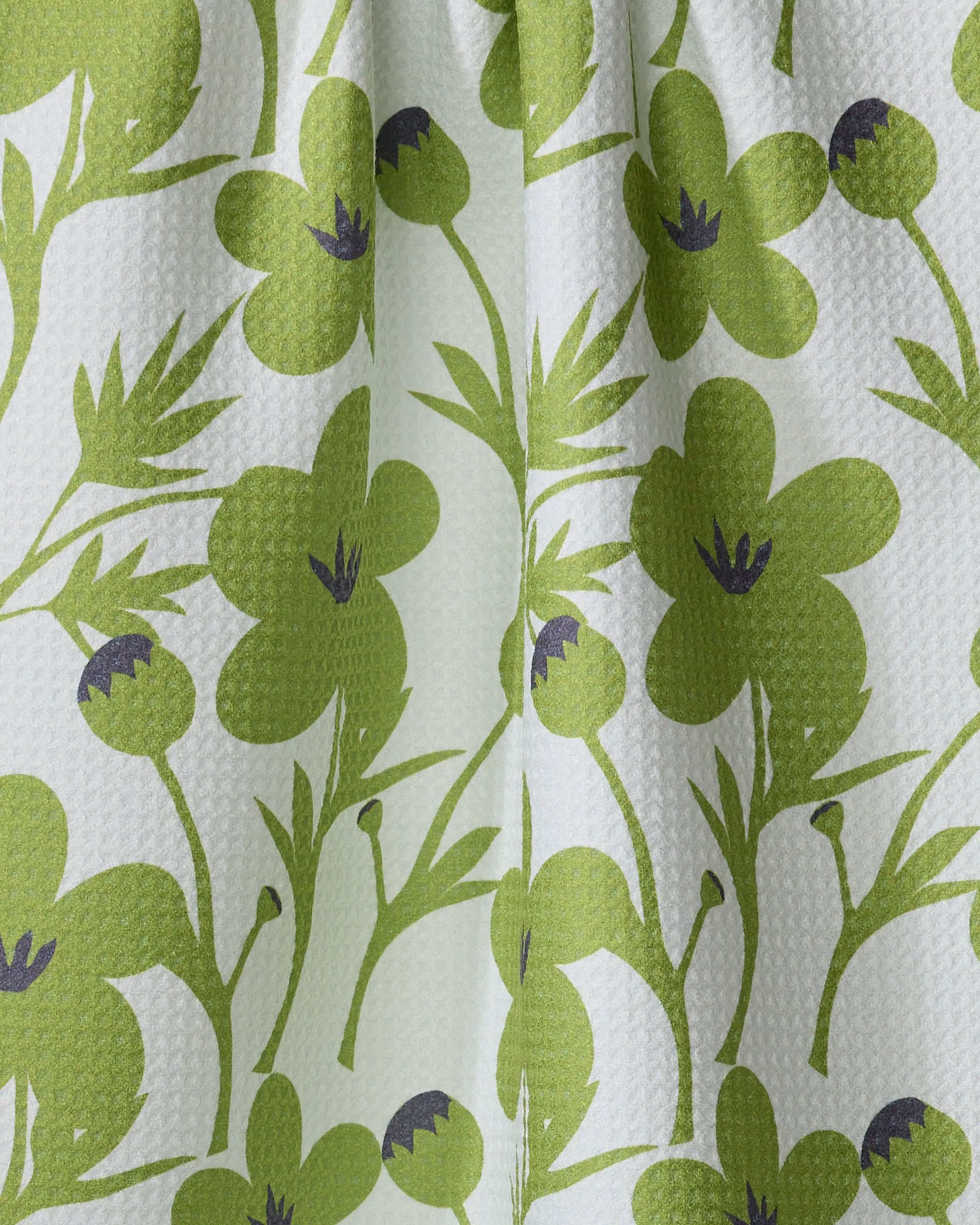 Close-up of the "Blooming Blossoms" kitchen towel by Lizzie Clark, featuring a green floral design with large flowers and leaves on a light background; crafted from recycled materials with a lightly textured waffle weave.