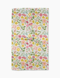 Blooming Days by Cottonflower Studio is a rectangular recycled kitchen towel with a vibrant, dense floral print—pink, yellow, and orange flowers with green leaves on white—covering the entire fabric.