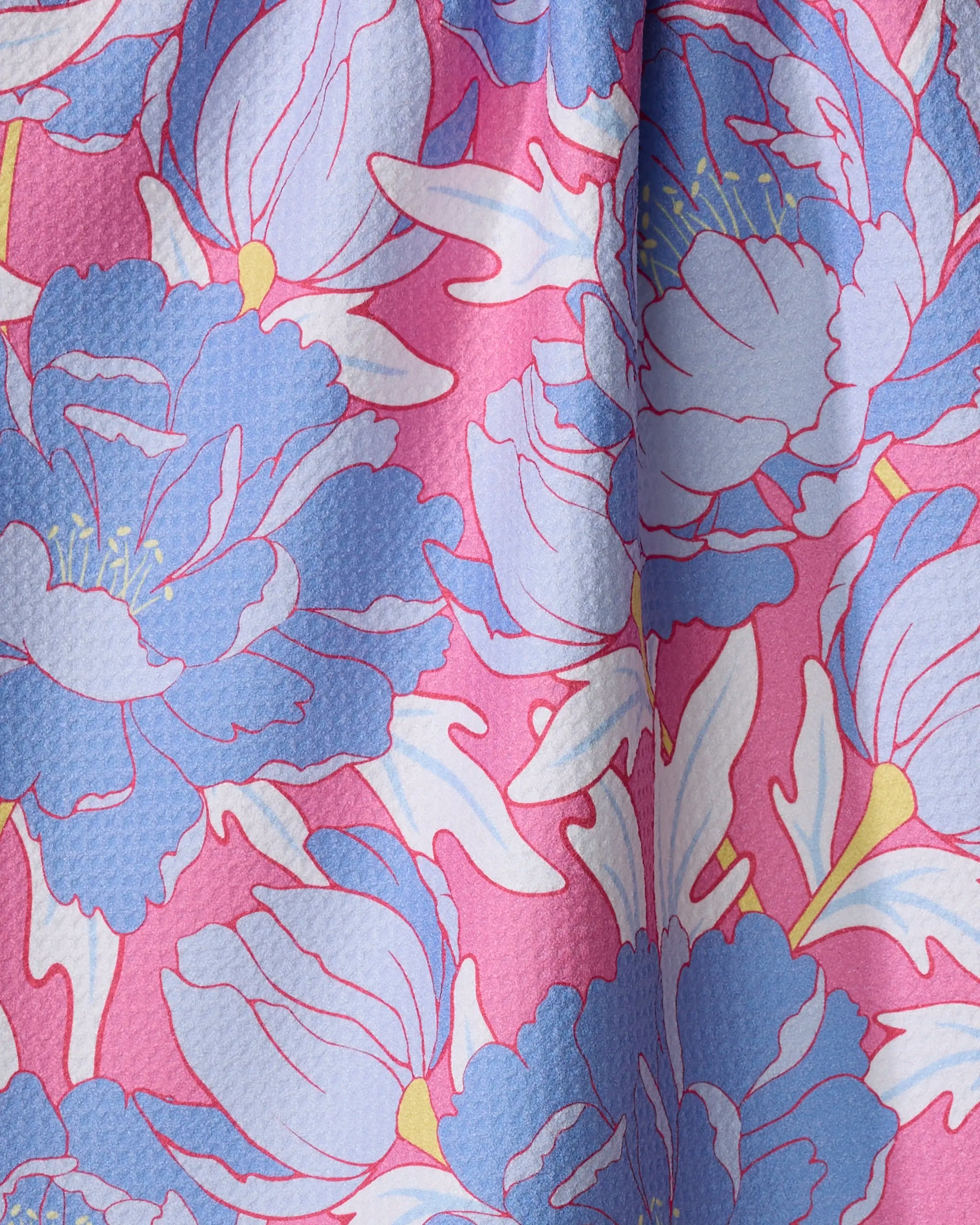 The Ashley Celena "Blooming Peonies" tea towel features large blue flowers with yellow centers and white leaves on a bright pink background, made from ultra-absorbent, recycled fabric with a slightly textured finish.