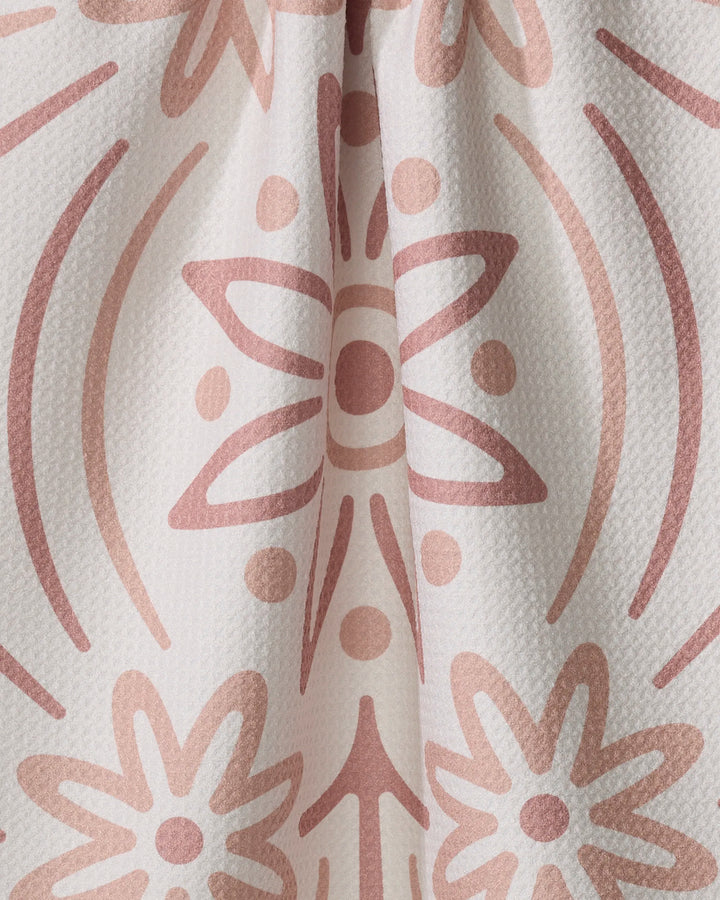Close-up of the Blossom tea towel by Adam Nienow, crafted from recycled materials with textured white fabric and a decorative pattern of pinkish-brown abstract floral motifs, dots, and curved lines.