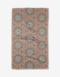 The Blue Aster Foxtrot by Katherine Berkeley is a rectangular rug with blue, green, and red starburst circles linked by red lines on a cream background. Crafted from recycled materials, its repeating geometric pattern adds artistic flair.