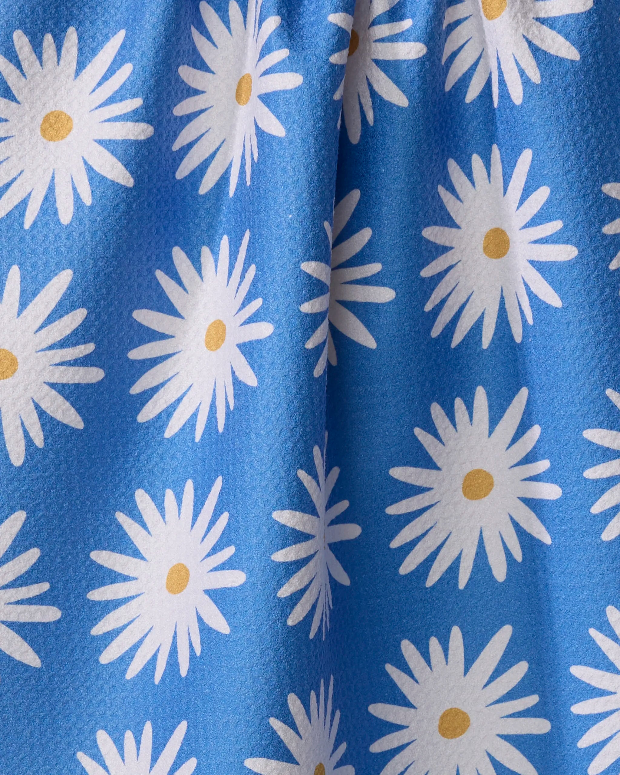 Close-up of Megan Roy's Blue Daisies Geoweave fabric, featuring white daisies with yellow centers on blue. Soft gathers add texture—ideal for an eco-friendly tea towel.