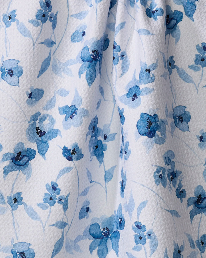 Aubrey Fairchild’s Blue Floral tea towel features a white textured fabric with watercolor-style blue flowers and leaves, absorbing spills while adding elegance to your kitchen.