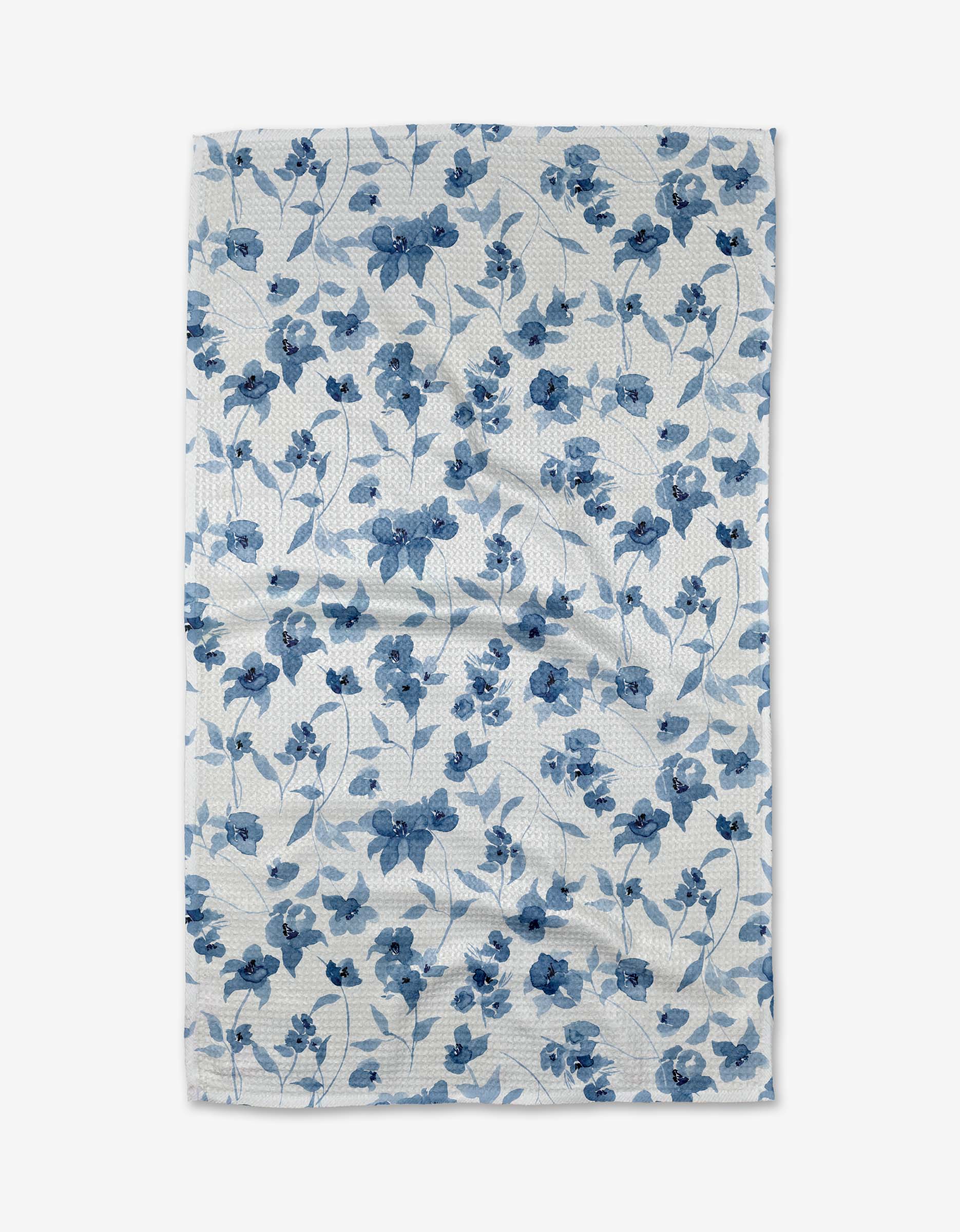 The Aubrey Fairchild Blue Floral tea towel features a blue flower and leaf pattern on white Geoweave fabric, shown laid flat with slight wrinkles.