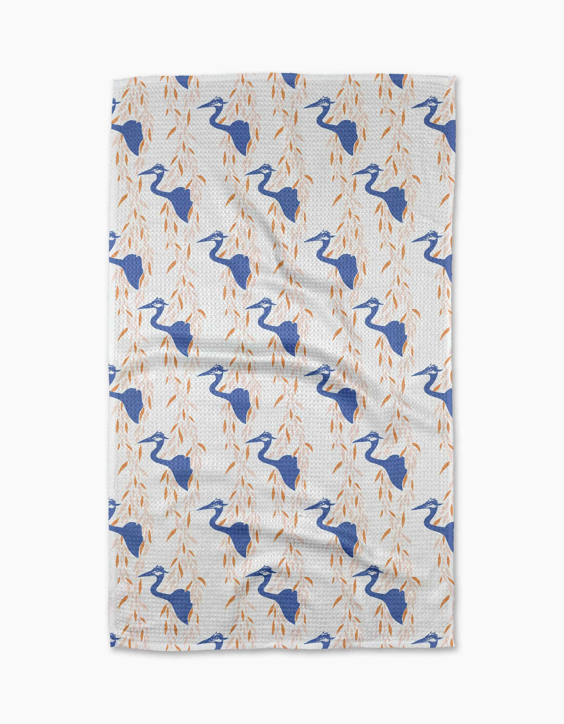 The Blue Heron tea towel by Elisabeth Wing showcases blue herons among orange leafy branches, arranged in a diagonal pattern across white eco-friendly fabric.