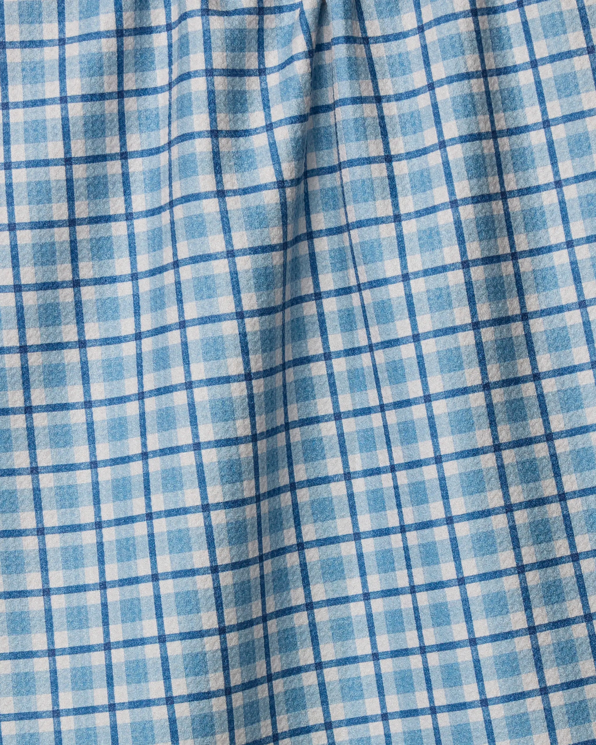 Close-up of the Geometry Bluefield tea towel, featuring a blue and white plaid checkered pattern. Slightly wrinkled, it shows soft folds and texture—making this eco-friendly towel an absorbent choice for your kitchen.