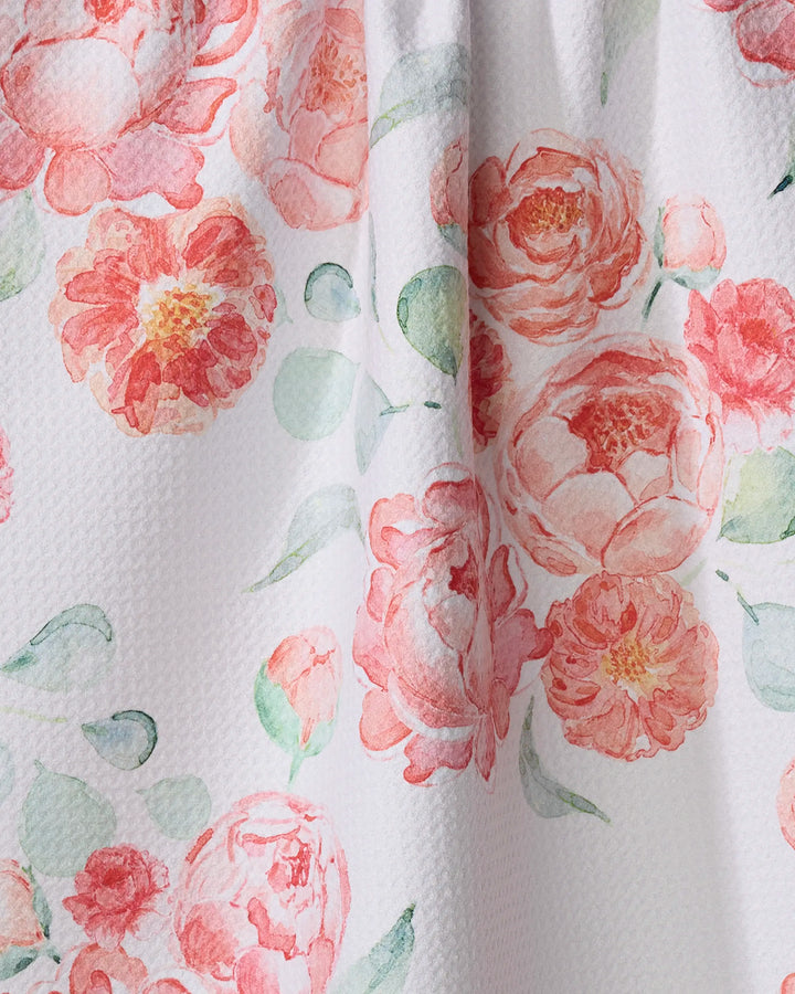A close-up of the Elena Fay "Blush Florals" kitchen towel, made from recycled materials and featuring pink and peach watercolor-style flowers with green leaves on a white textured background.
