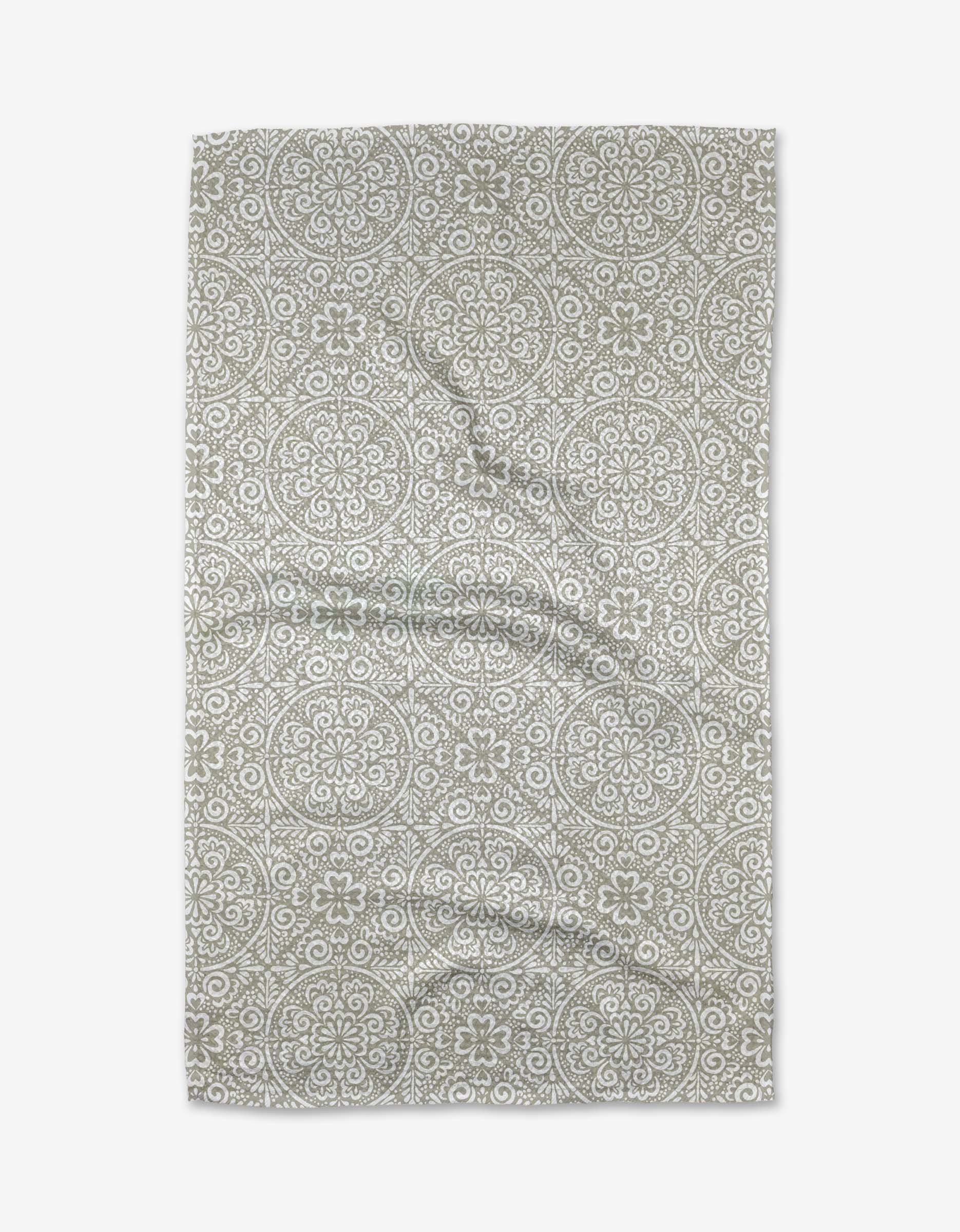 The Boho Medallion tea towel by Kris Ruff features a light beige background with intricate white floral and circular geometric patterns. Made from ultra-absorbent recycled materials, it showcases a stylish boho look when laid flat with gentle wrinkles.