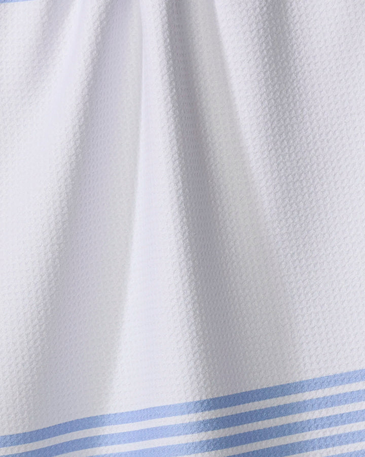 A close-up of The Buy Guide's Bold Blank Space - French Blue tea towel, featuring white textured fabric with French blue stripes along the bottom and soft folds that highlight its ultra-absorbent finish.