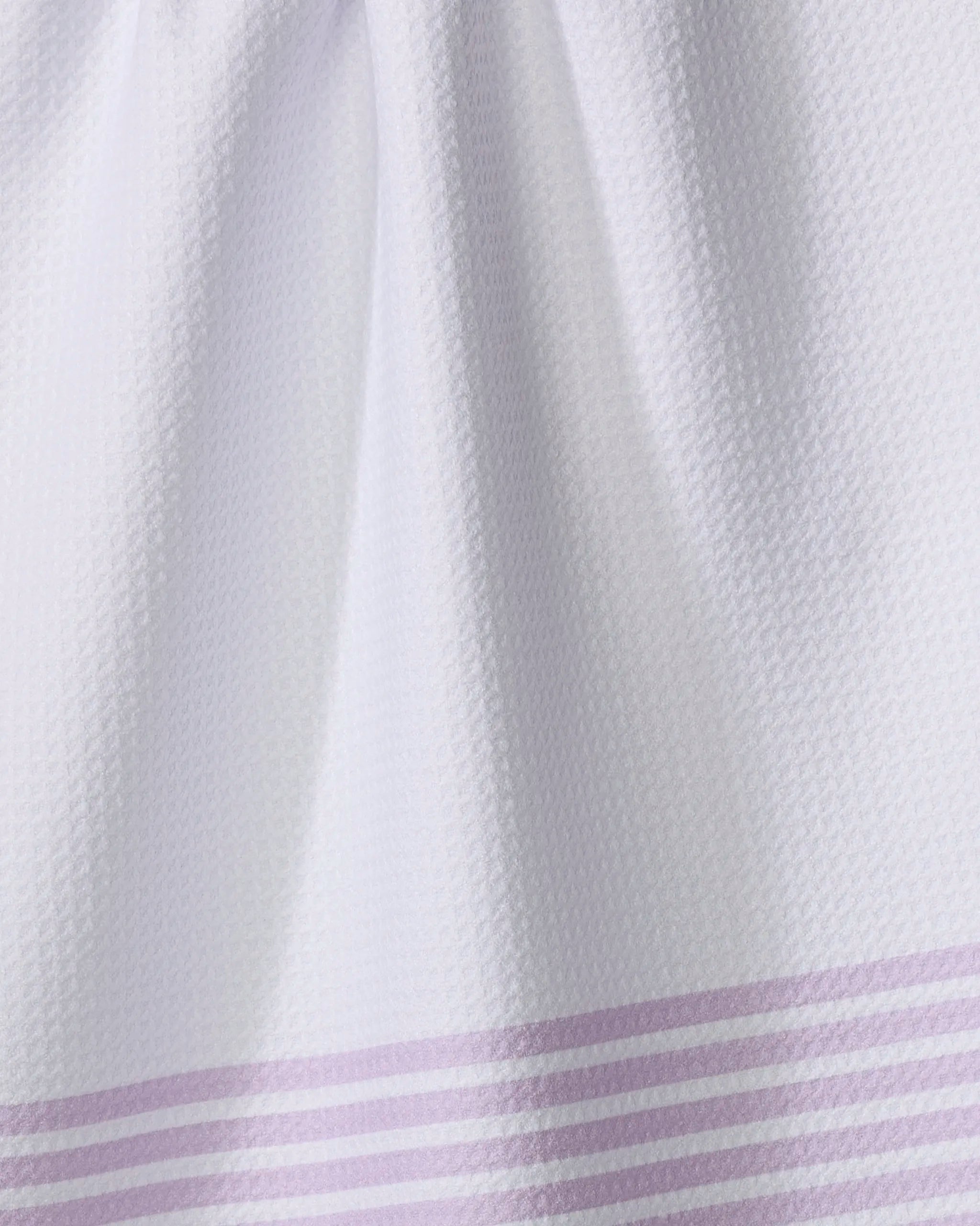 Close-up of The Buy Guide's Bold Blank Space - Lilac tea towel, crafted from ultra-absorbent recycled materials, with parallel light purple stripes near the bottom edge and a white textured finish.