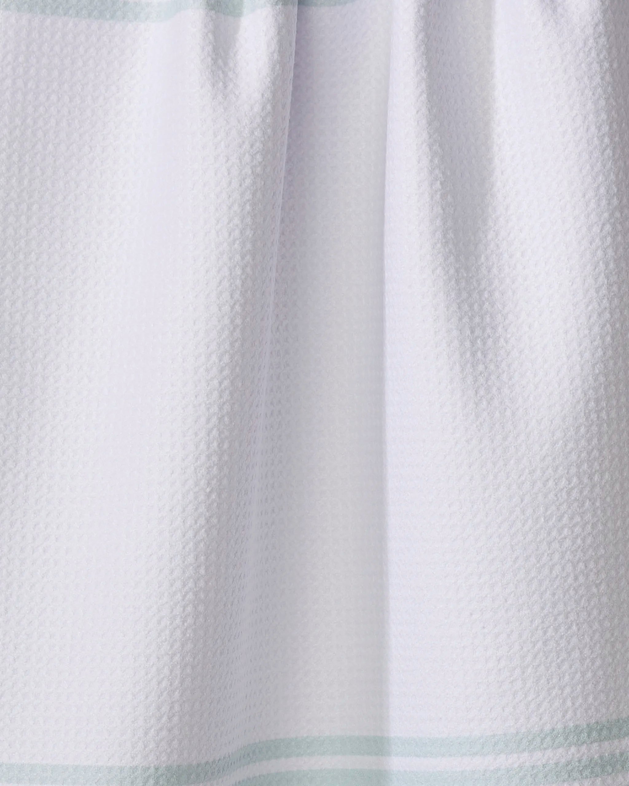 Close-up of The Buy Guide’s Bold Blank Space - Mint tea towel, featuring a white textured fabric with subtle mint stripes near the top and bottom. The ultra-absorbent towel is shown slightly gathered at the upper edge.