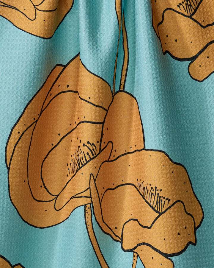 A close-up of the Julianne Haness "Bold Peonies" tea towel, featuring a textured surface with bold peony flowers on a light blue background and made from recycled materials.