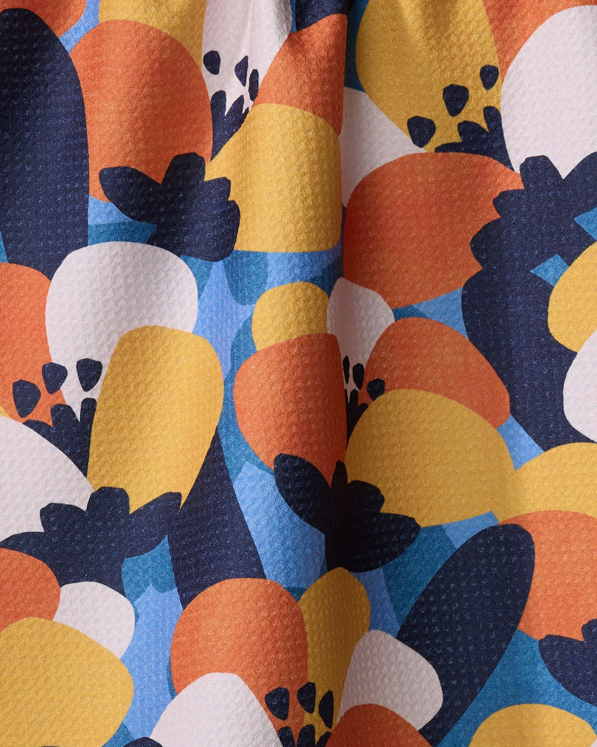 Bold Petal Bloom by Claire Iglesias is an ultra-absorbent tea towel featuring colorful, overlapping yellow, orange, blue, white, and black shapes in rounded and leaf-like forms for a playful, modern look.