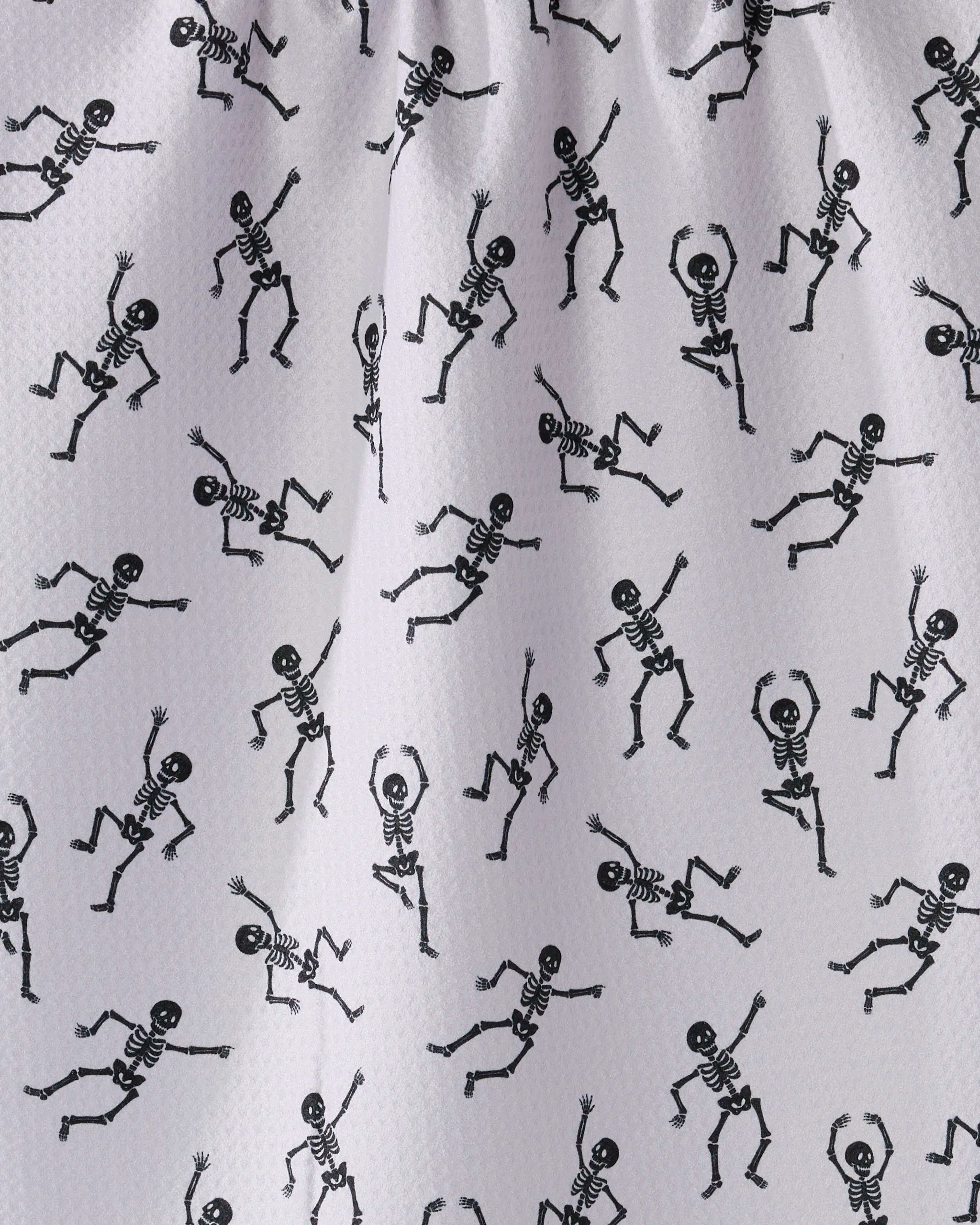 Geometry’s Bone Jamboree tea towel features black cartoon skeletons in playful poses on white textured fabric, crafted from recycled materials.