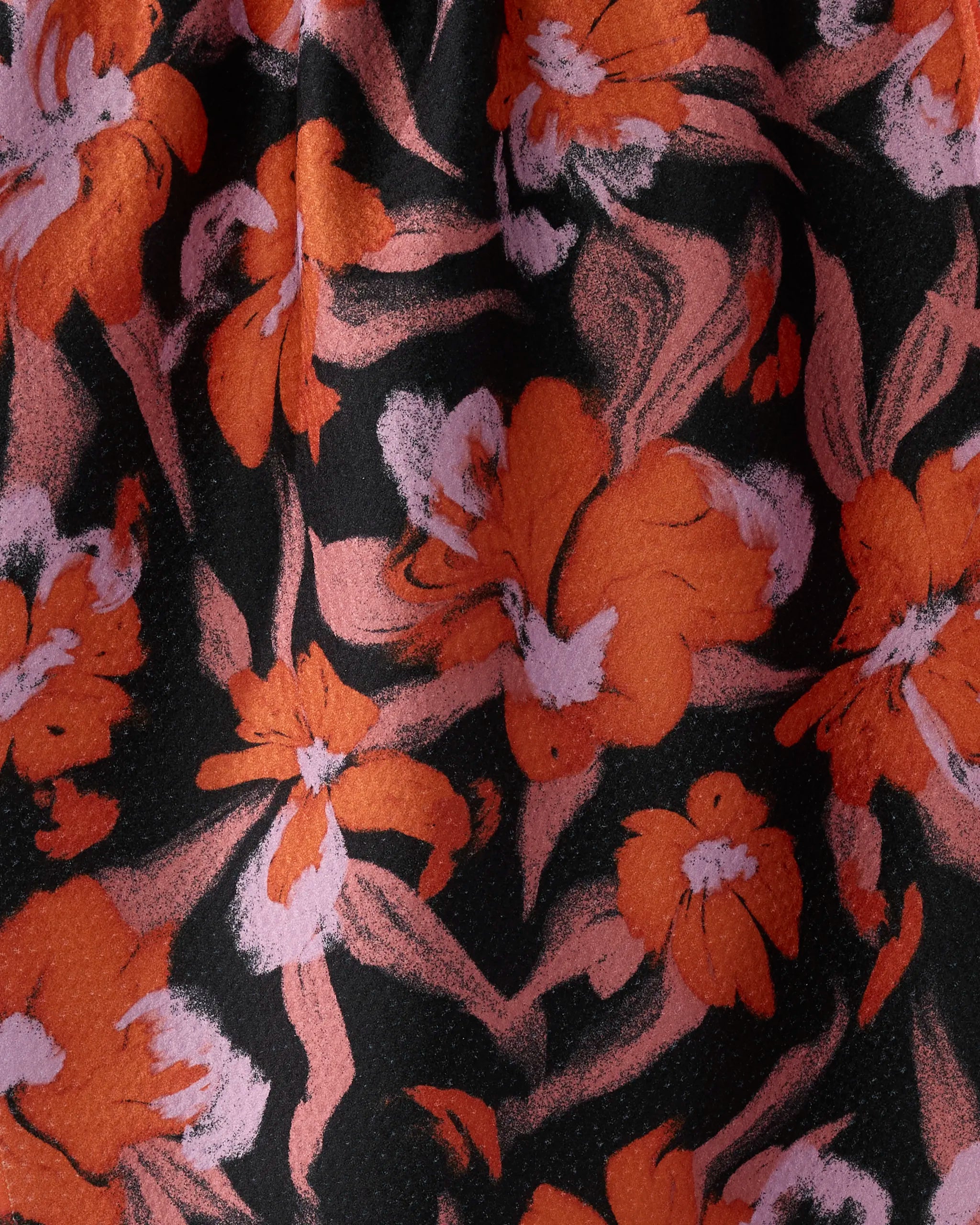 A close-up of Geometry’s "Boo-tanical" tea towel, made from recycled materials and featuring a bold floral pattern with large orange flowers, white accents, and pink brushstrokes on a black background.