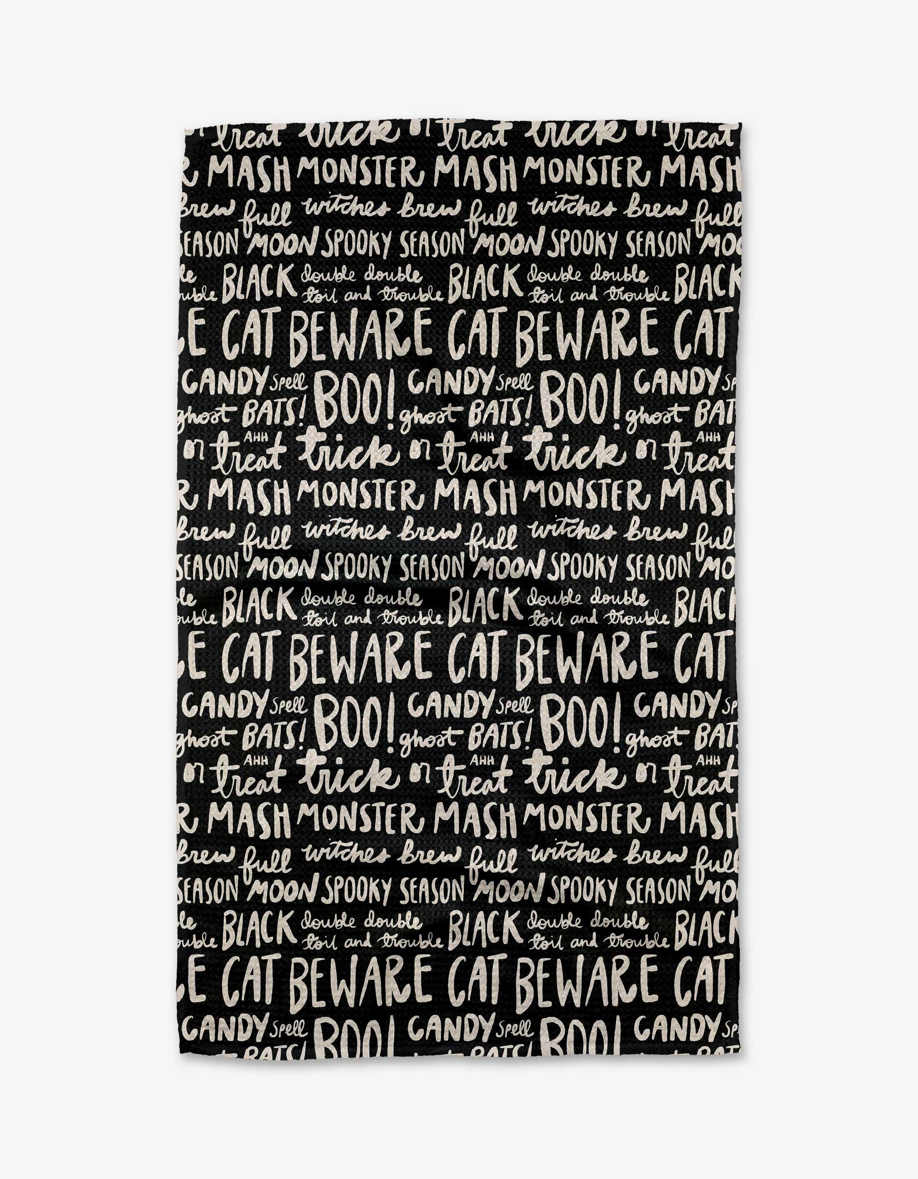The Booos by Kayla Ann is a black tea towel made from recycled materials, decorated with white, hand-lettered Halloween-themed words like trick, BOO!, and monster mash in assorted fonts and sizes.