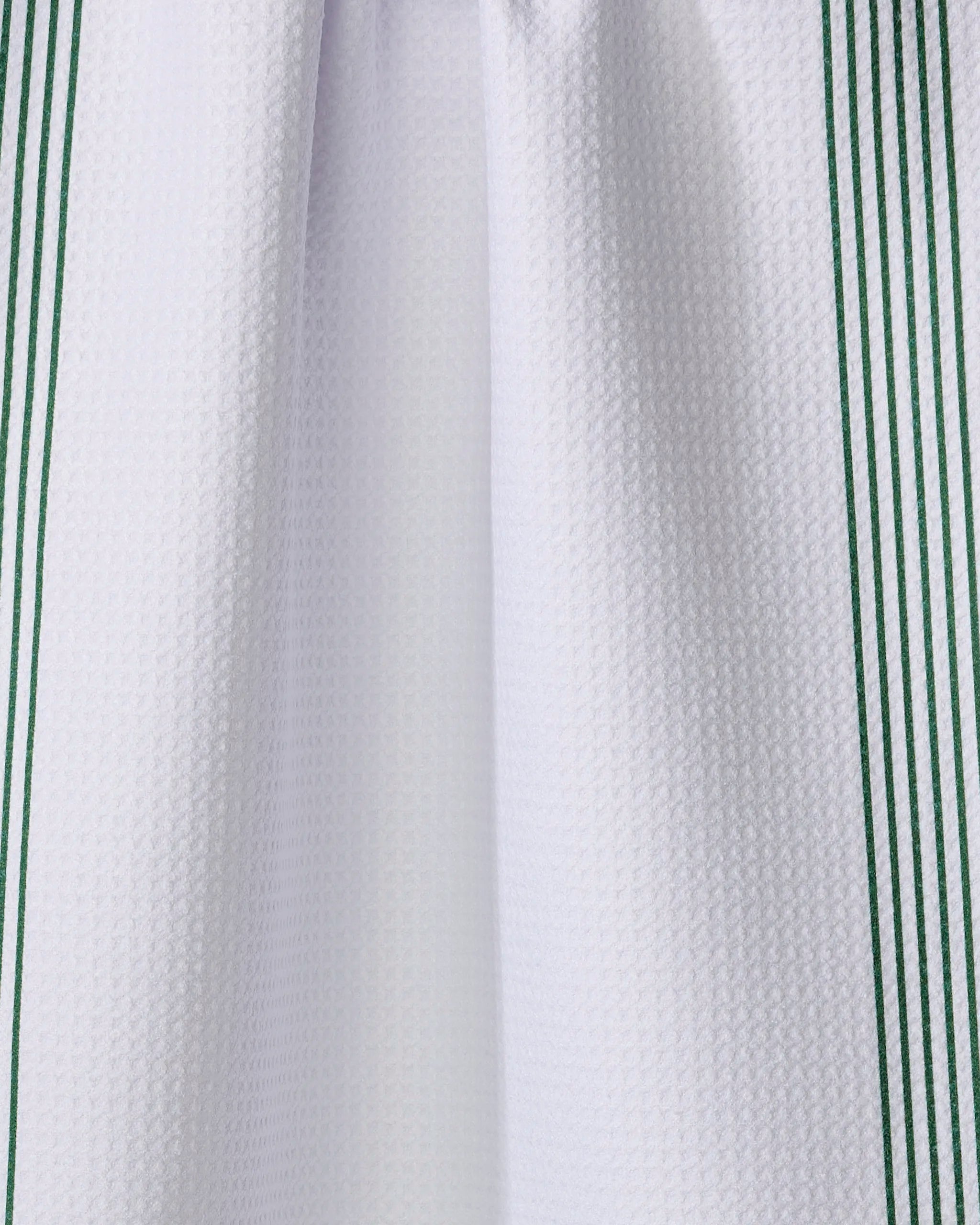 A close-up of The Buy Guide’s Borderline - Evergreen kitchen tea towel, featuring white textured fabric with vertical green stripes along the edges, crafted from recycled materials.