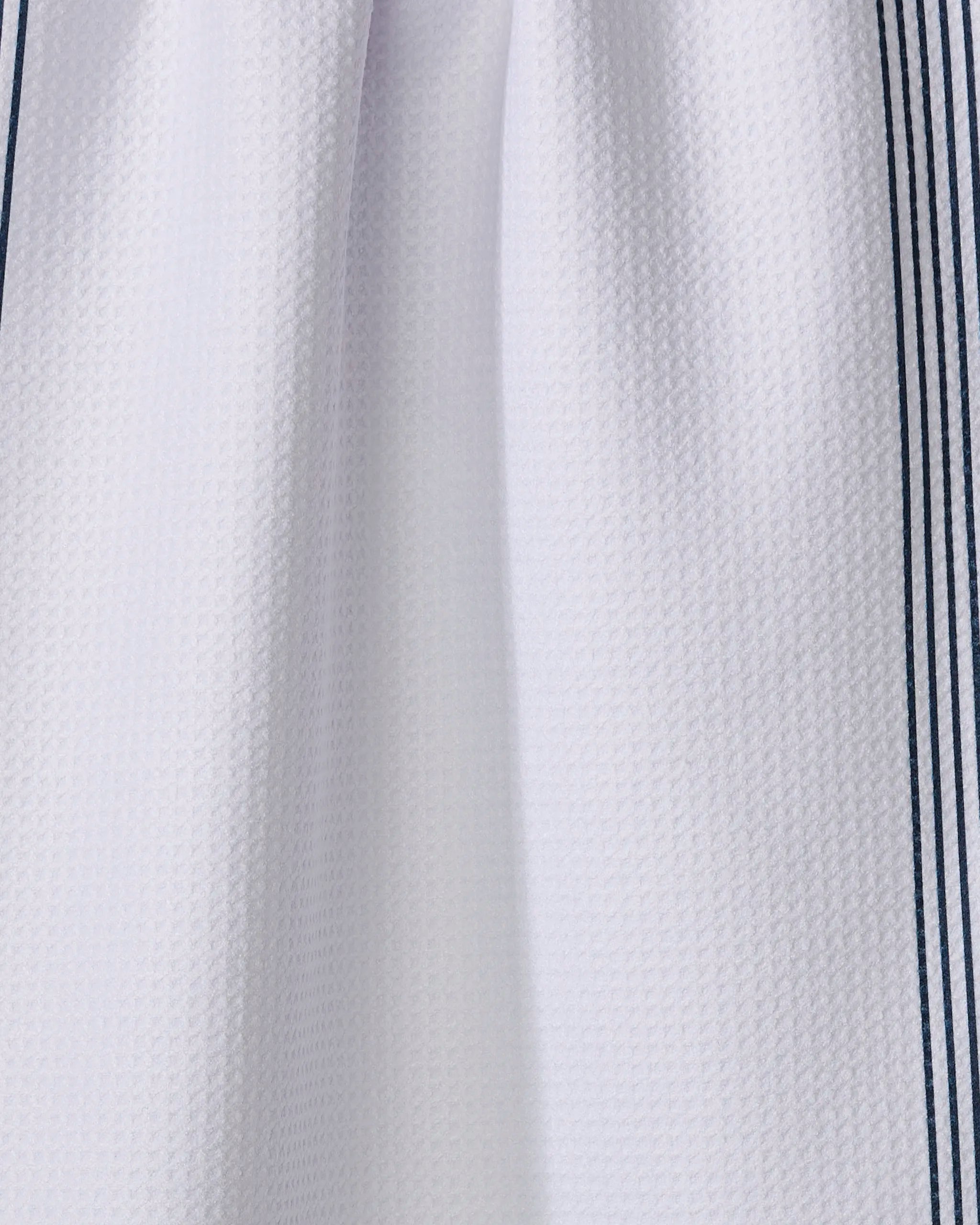 Close-up of The Buy Guide’s Borderline - Navy towel, featuring a white waffle-textured fabric with two thin navy stripes on each side. Made from recycled materials, the ultra-absorbent towel is slightly gathered at the top center.