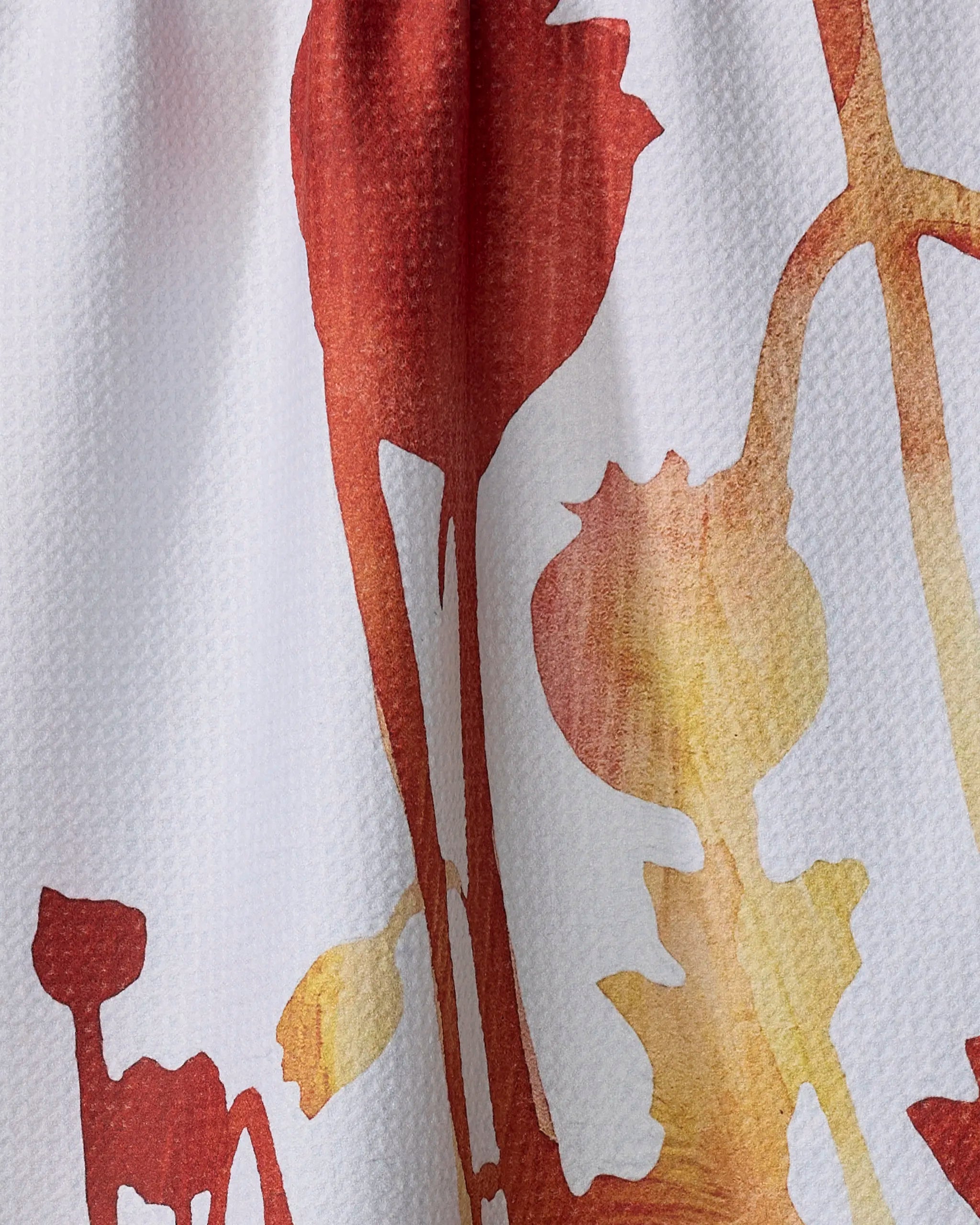 A close-up of the Rachel Austin "Botanical Watercolor Dusk" towel, an absorbent quick-drying towel with a textured surface and a red and yellow abstract floral print on white.