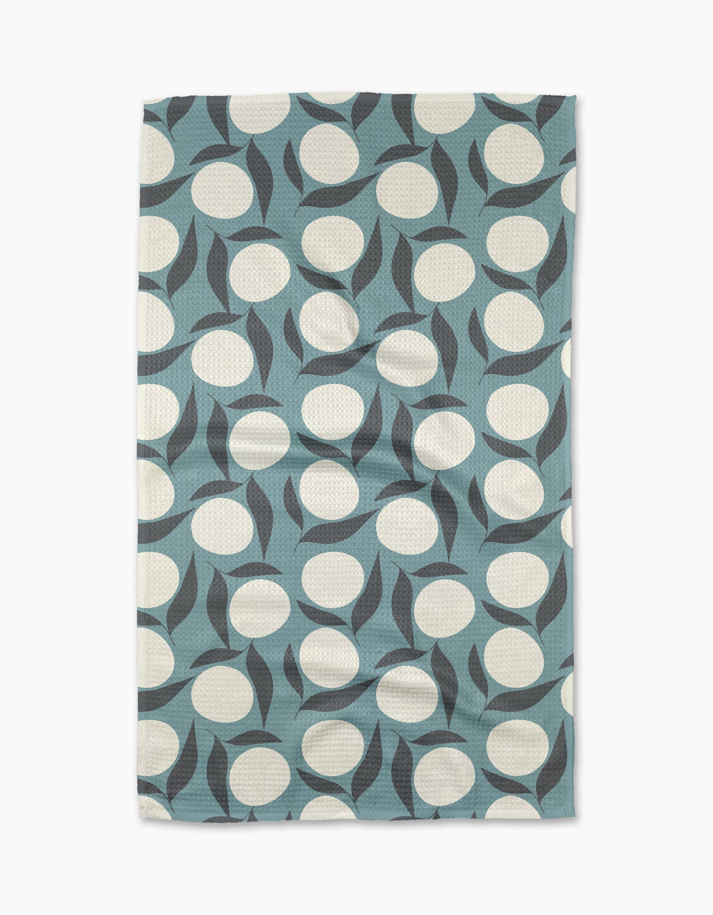 The “Bouncing Blooms” tea towel by Lizzie Clark is a rectangular, blue recycled towel with large white circles and curved black shapes in a modern abstract geometric pattern.