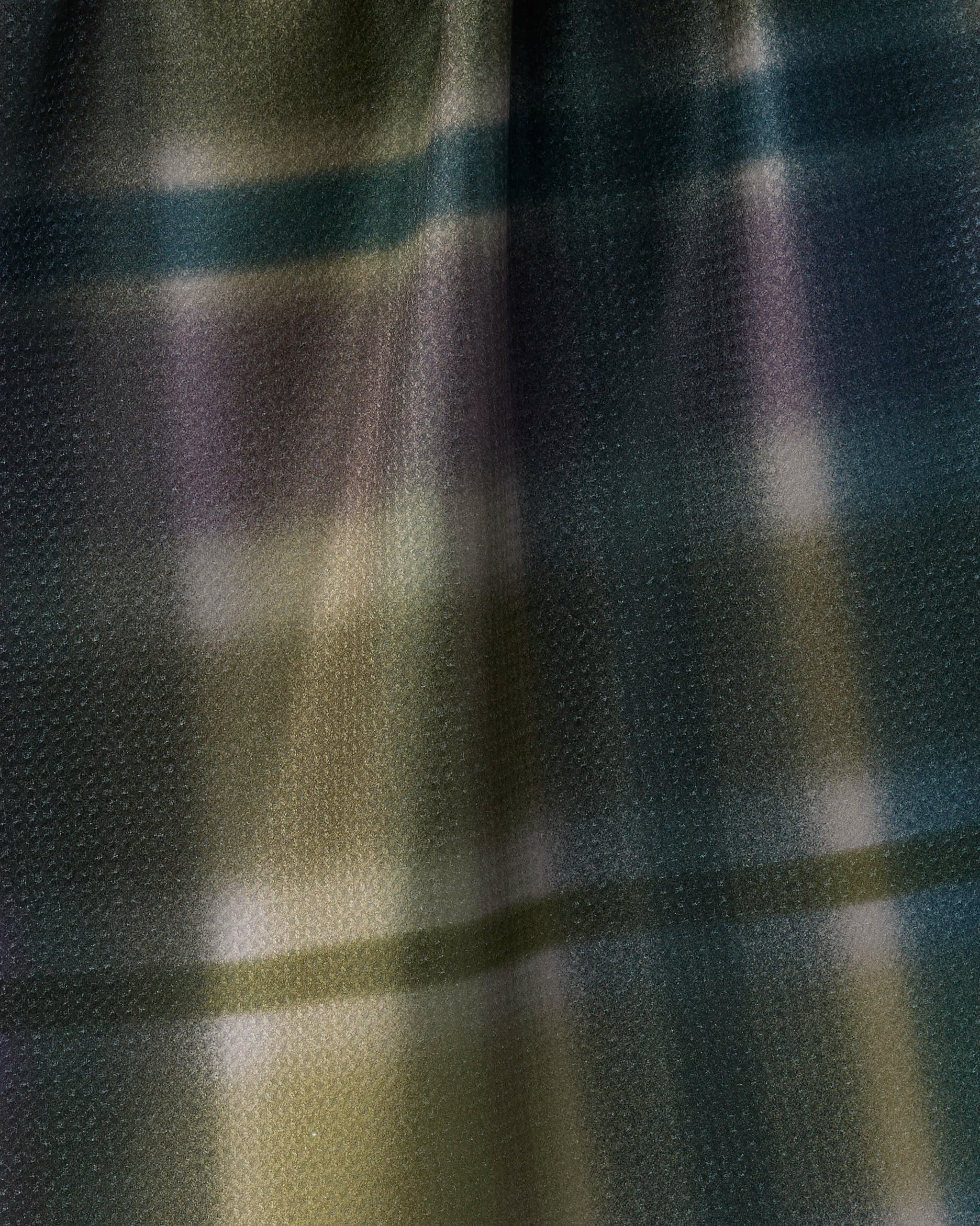 Close-up of Geometry’s Bracken recycled kitchen towel, featuring a muted plaid pattern in green, purple, black, and yellow tones. The surface is smooth with a subtle dotted texture and a slight sheen.
