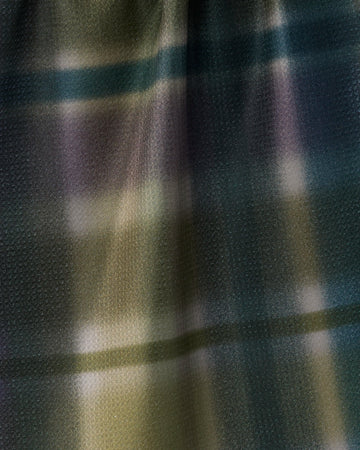 Close-up of Geometry’s Bracken recycled kitchen towel, featuring a muted plaid pattern in green, purple, black, and yellow tones. The surface is smooth with a subtle dotted texture and a slight sheen.