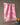 A Geometry Bramble Pink tea towel with pink floral patterns hangs on a clothesline. In front, a blue ceramic bowl filled with walnuts stands out against a softly lit, neutral background.