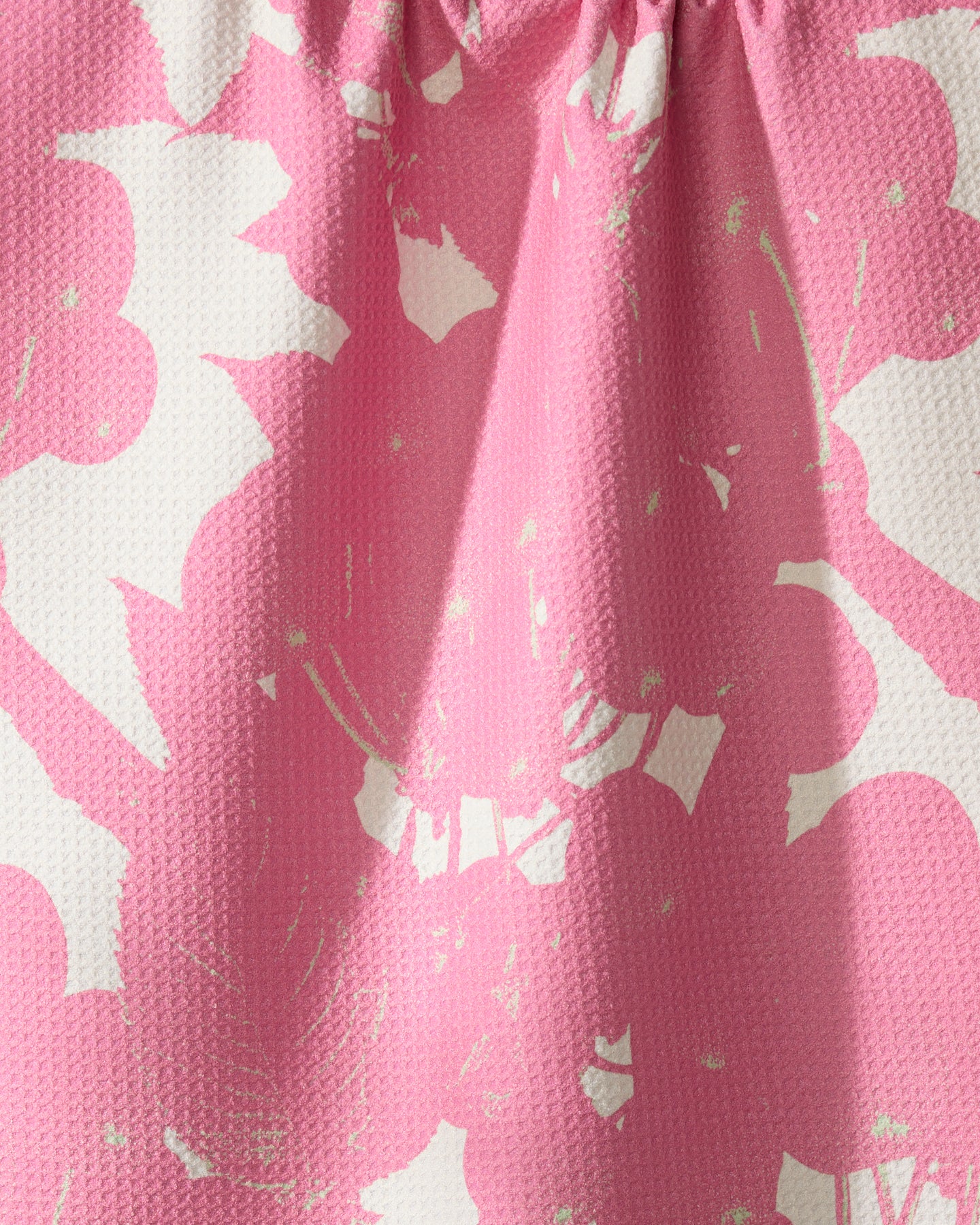Close-up of Bramble Pink by Geometry: textured, ultra-absorbent towel fabric with a pink and white floral pattern, softly gathered at the top to create gentle folds and shadows.