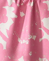Close-up of Bramble Pink by Geometry: textured, ultra-absorbent towel fabric with a pink and white floral pattern, softly gathered at the top to create gentle folds and shadows.