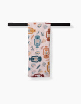 The Twig + Spark Bright Spot tea towel, featuring a geometric lantern and leaf pattern in blue, orange, and red, hangs neatly folded over a horizontal black bar against a white background.