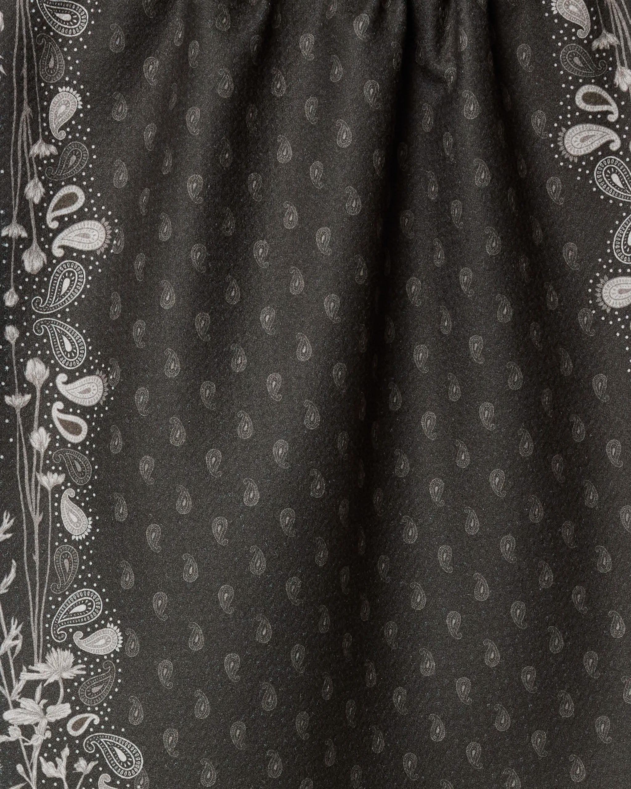 Close-up of Geometry’s Bronco Espresso recycled kitchen towel, featuring dark fabric with a subtle paisley center and intricate light floral and paisley edge designs. Gathered texture adds elegance, perfect as an eco-friendly tea towel.