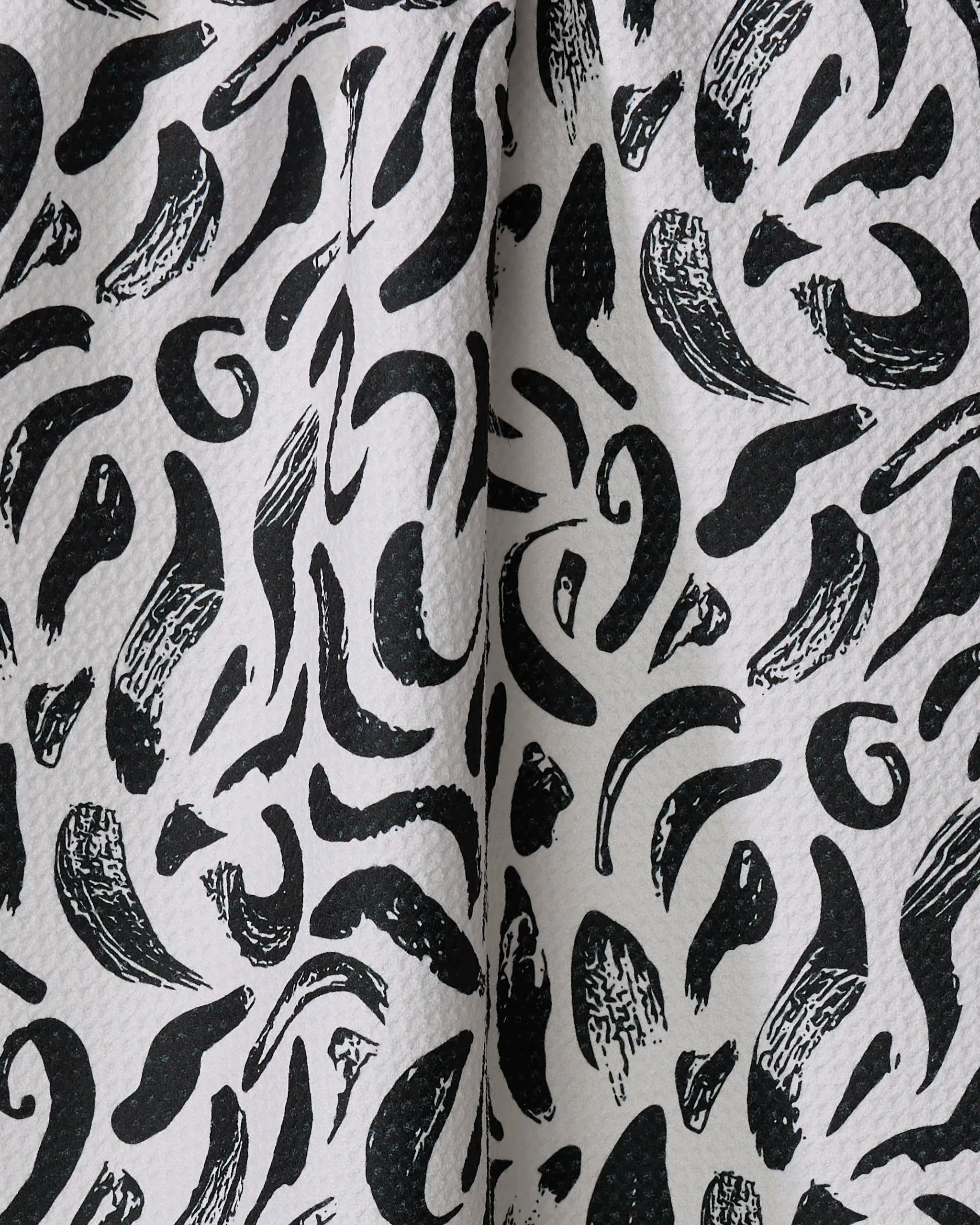 The Brush Strokes Swirls tea towel by Sarah Daugherty features abstract black curved and brushstroke patterns on white, crafted from recycled materials.