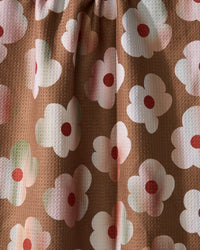 Geometry’s Brushed Bouquet Brown features brown eco-friendly fabric with white flowers, pink centers, and red dots. Soft folds and subtle shadows create a 3D effect—perfect for a charming kitchen towel.