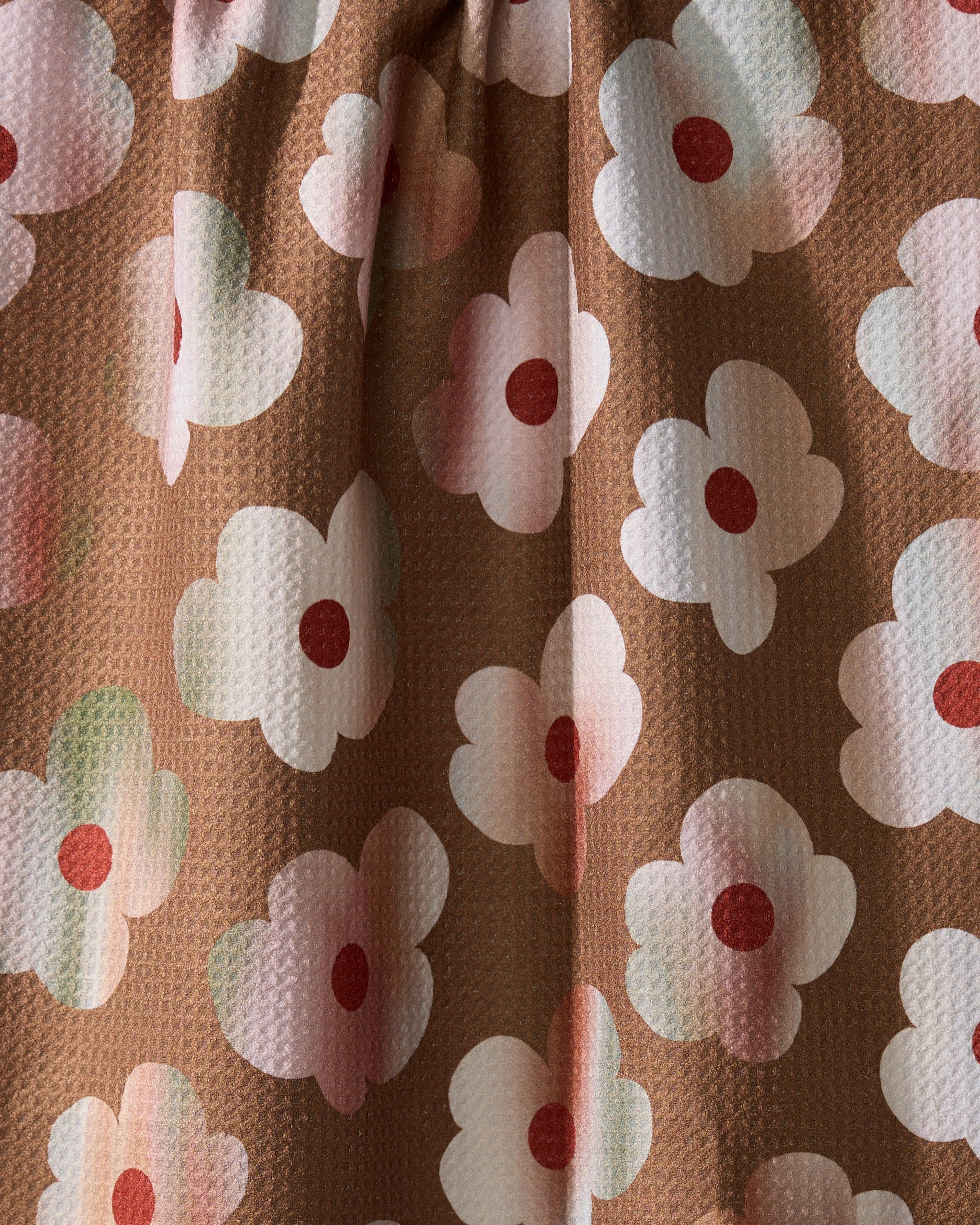 Geometry’s Brushed Bouquet Brown features brown eco-friendly fabric with white flowers, pink centers, and red dots. Soft folds and subtle shadows create a 3D effect—perfect for a charming kitchen towel.
