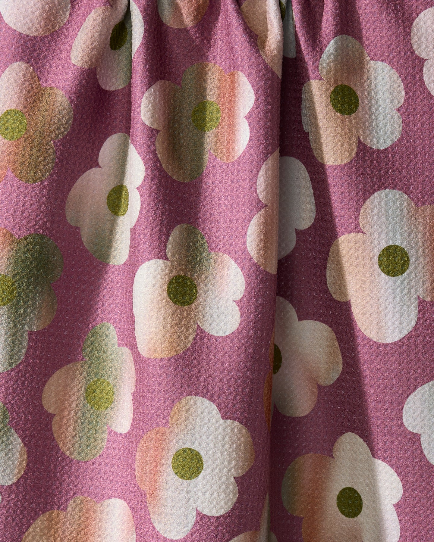 Close-up of the Geometry Brushed Bouquet towel, featuring ultra-absorbent textured fabric with white, green, and peach stylized flowers on a pink background. The kitchen tea towel appears slightly gathered at the top.