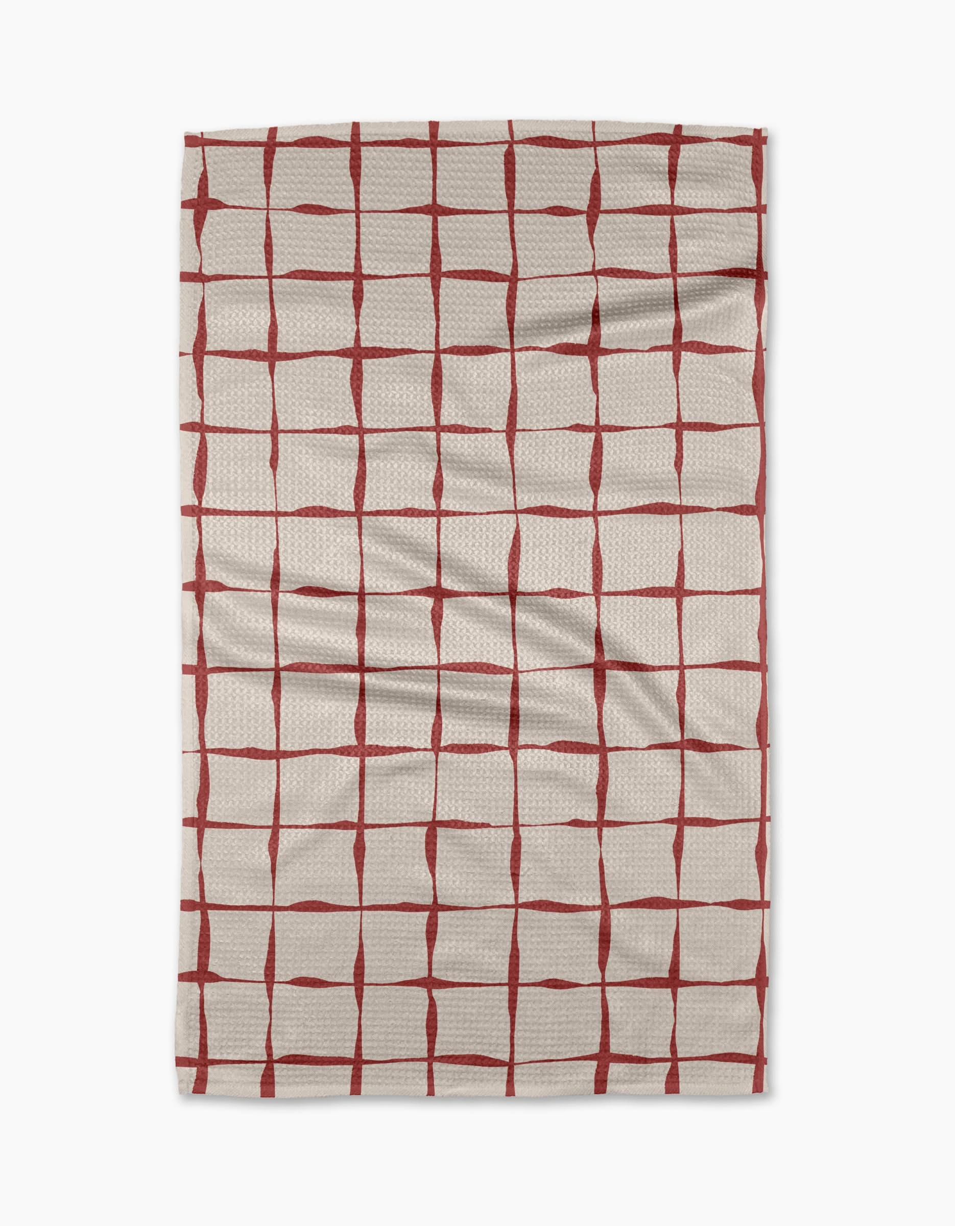 The Brushstroke Checks kitchen towel by Linda Fox is a beige, recycled fabric towel with irregular red grid lines and visible surface creases.
