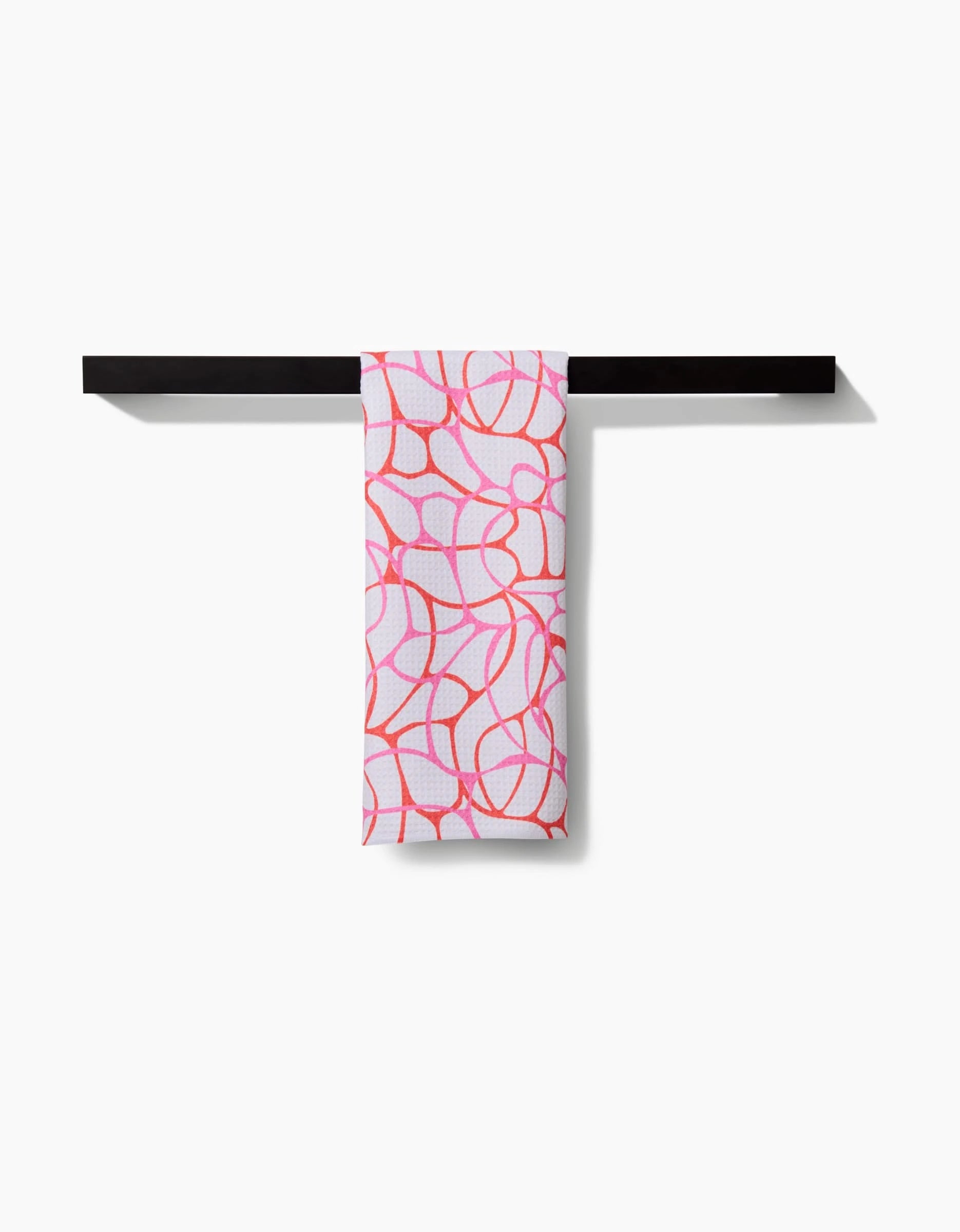 The Bubble Abstract tea towel by Rachel Parker, made from ultra-absorbent Geoweave fabric, features a bold pink and red abstract line design and hangs on a sleek black towel bar against a white background.